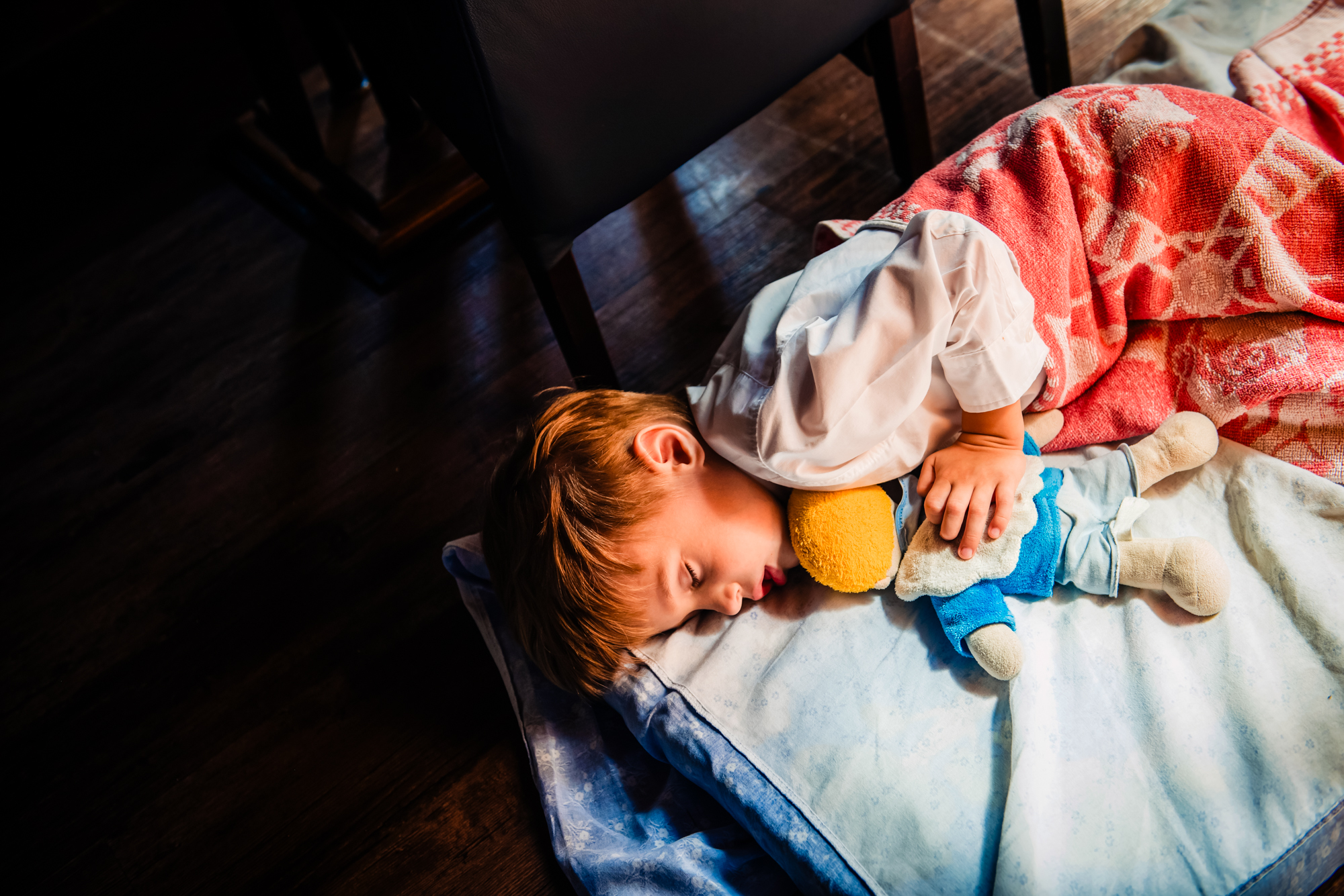 Tired little boy sleeping with soft toy during christening reception after church ceremony.