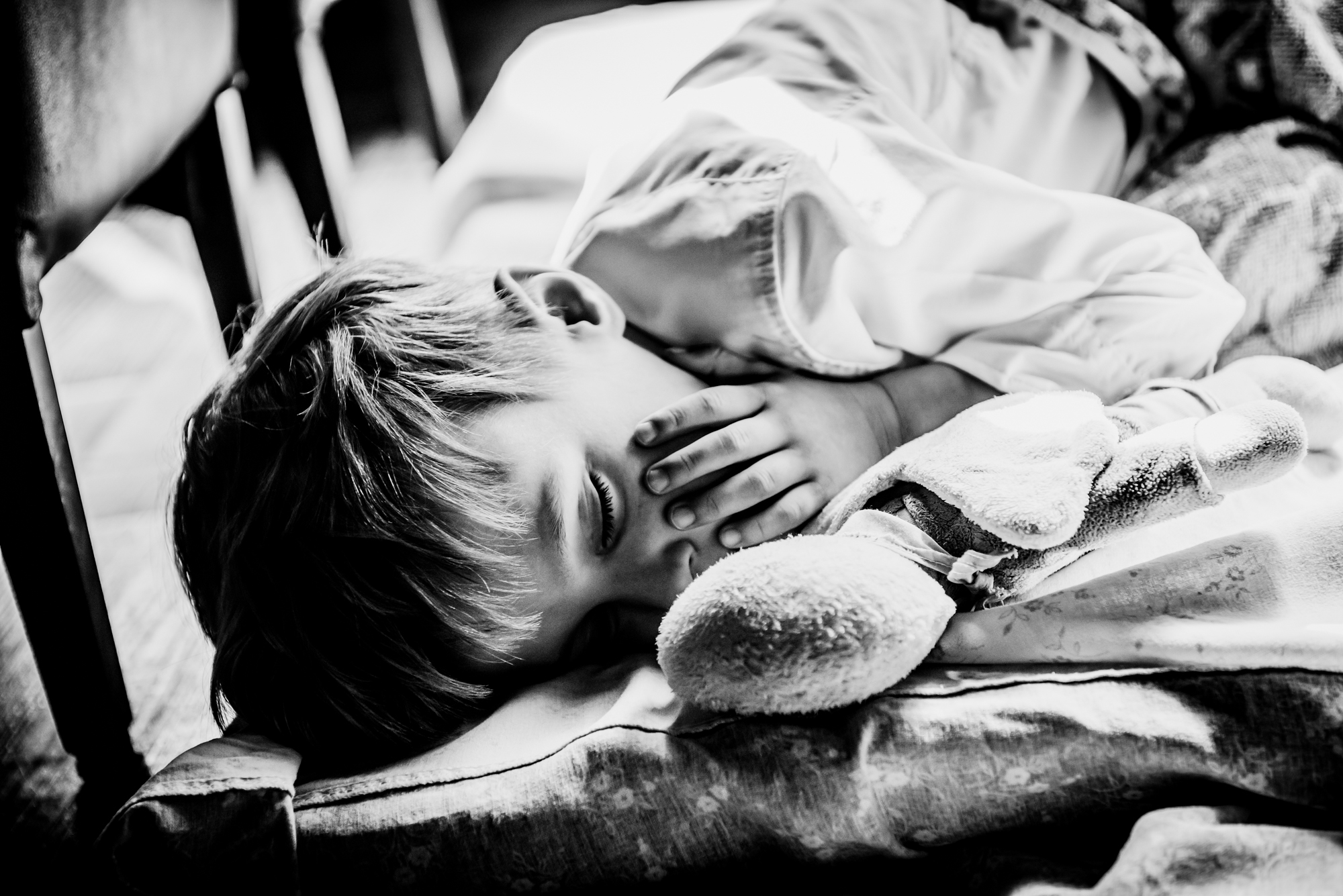 Sleeping child cuddling soft toy during quiet moment at christening reception.