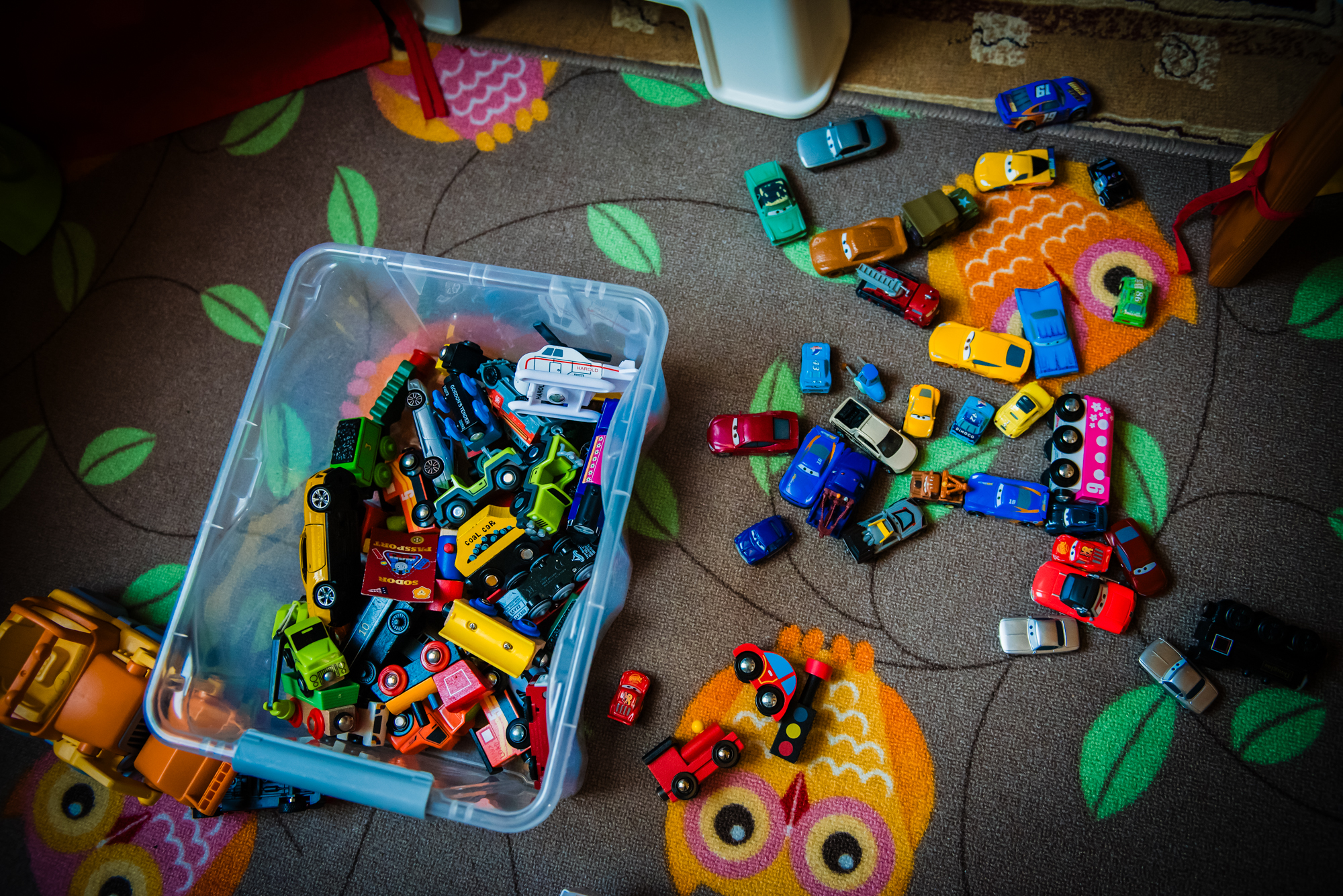 Collection of colourful toy cars scattered across a patterned rug in a child’s bedroom.