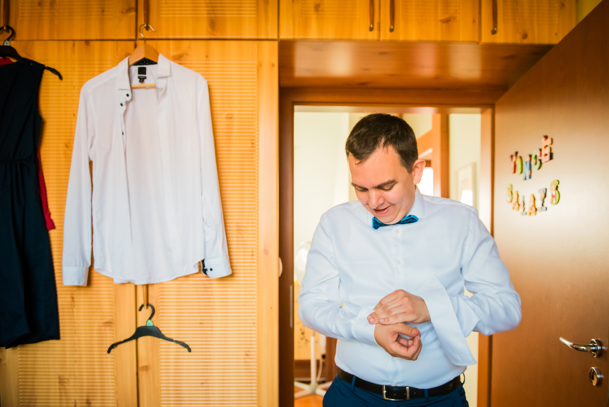 Father fastening cufflinks while getting dressed for his child’s christening at home.