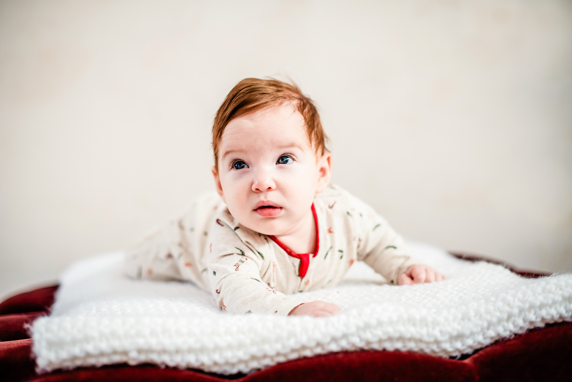 Baby Bella lies on a blanket in festive pyjamas during a Christmas baby studio session.