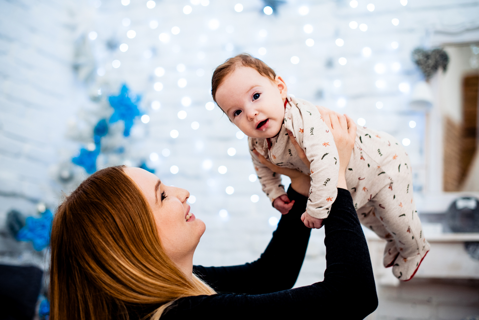 Baby Bella is lifted into the air by her mother during a joyful Christmas studio session.