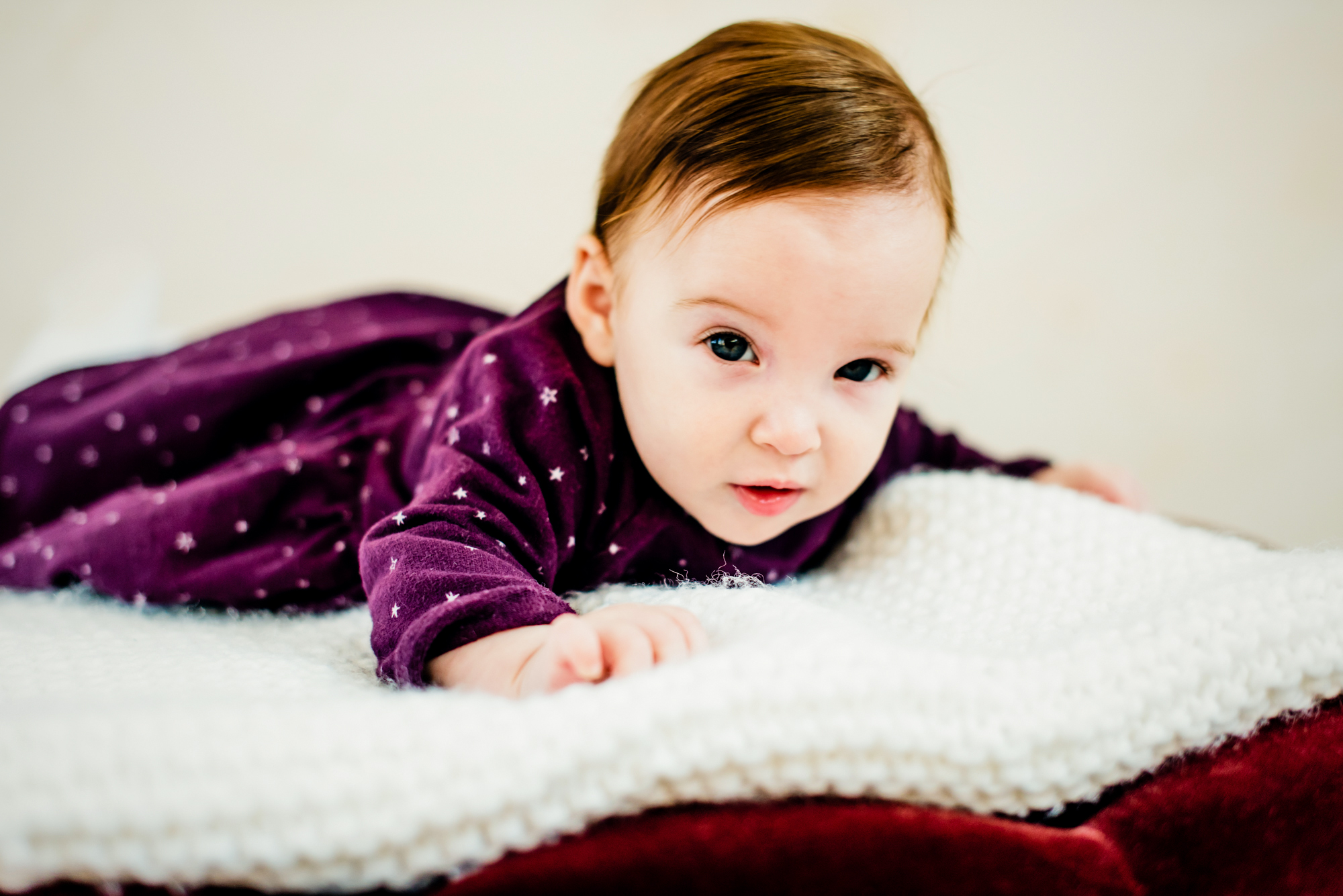 Baby Bella crawls forward on a soft blanket during a Christmas baby studio session.