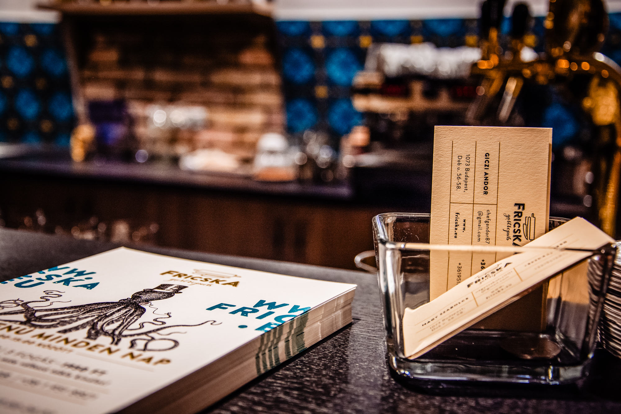 Fricska Gastropub business cards and flyers displayed on restaurant bar counter in Budapest.