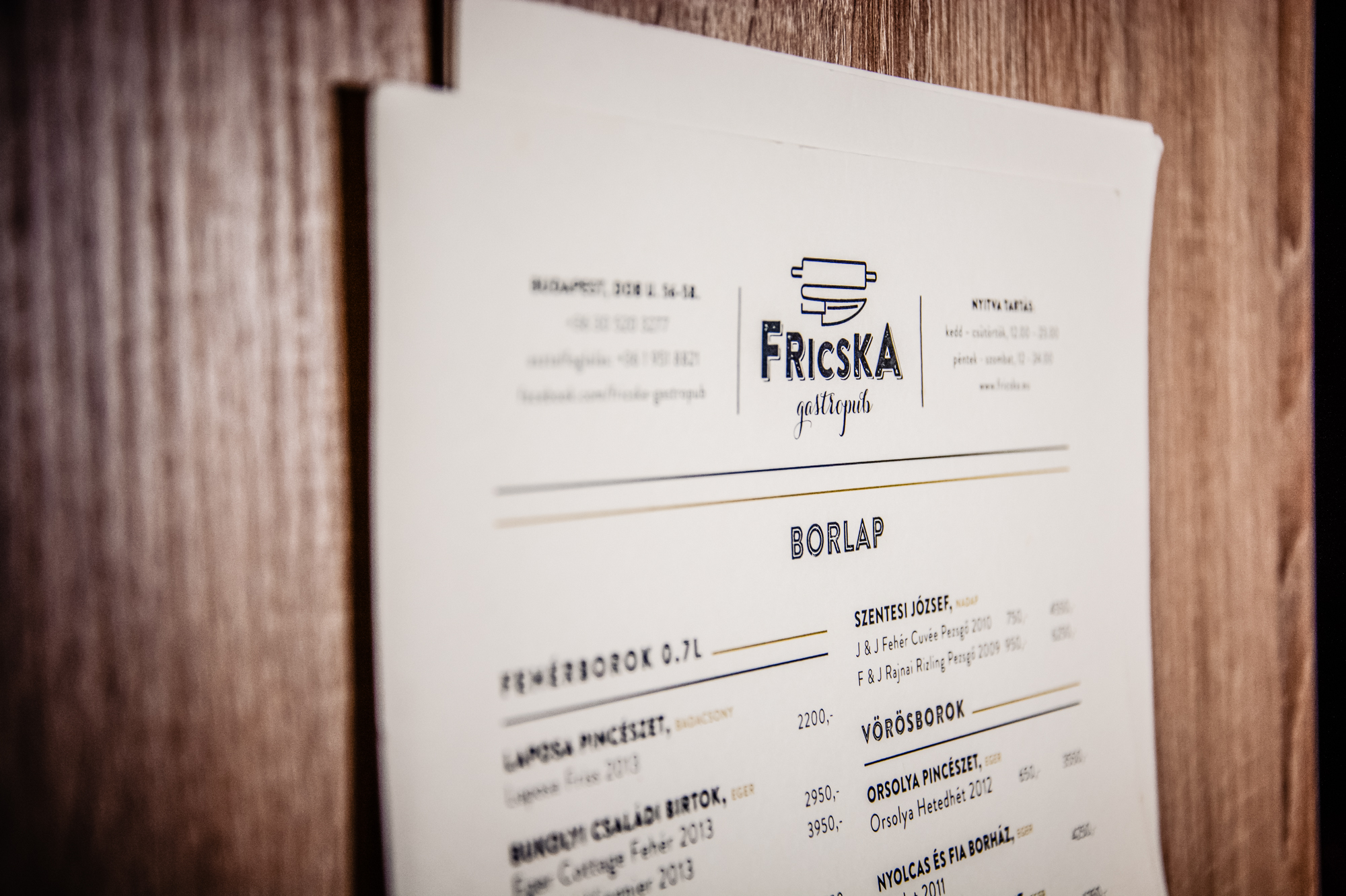 Fricska Gastropub wine menu mounted on wooden wall inside Budapest restaurant interior.
