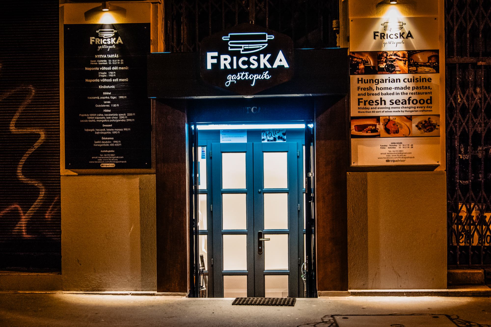 Illuminated entrance of Fricska Gastropub at night in central Budapest.