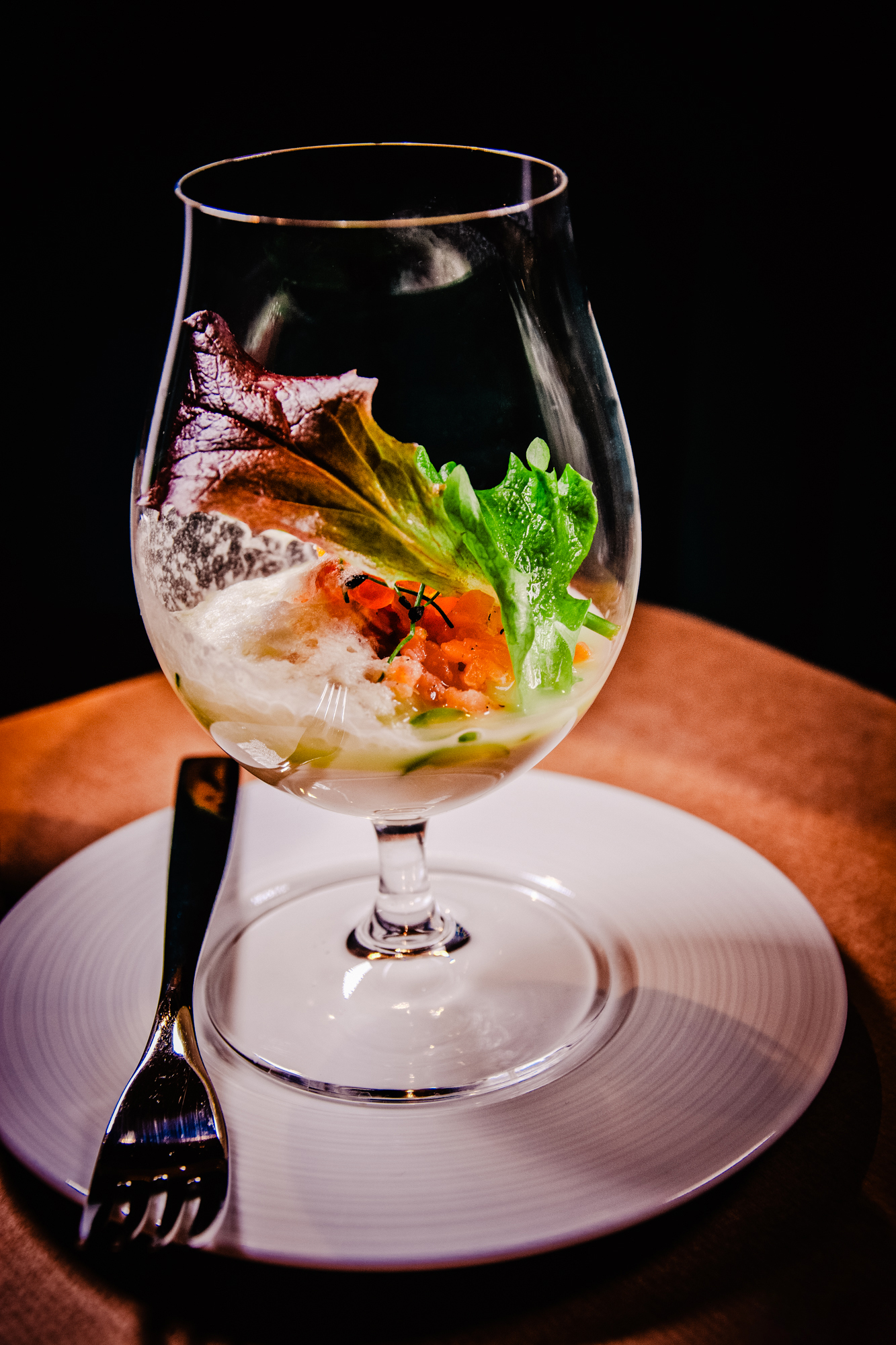 Salmon tartare with foam and lettuce served in wine glass.