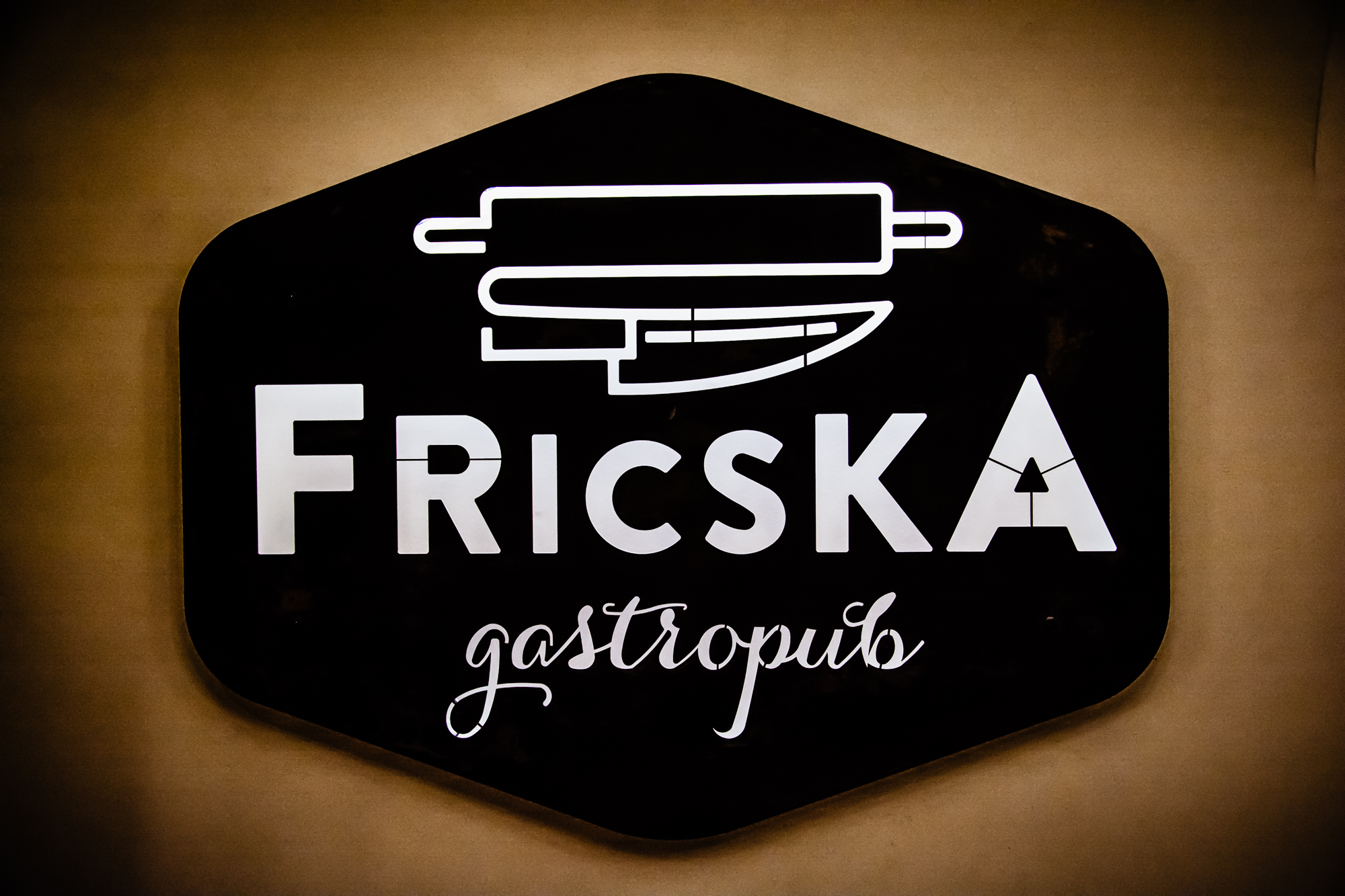 Illuminated Fricska Gastropub sign inside the Budapest restaurant photographed in warm ambient light.