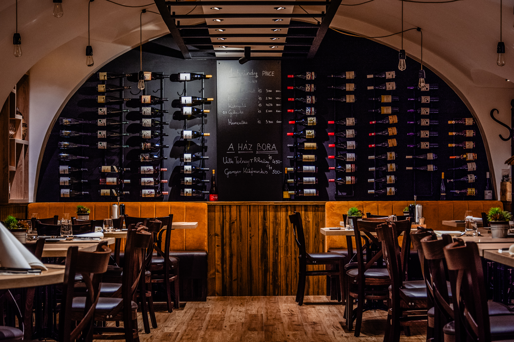 Wine wall and vaulted cellar dining room inside Fricska Gastropub, Budapest restaurant interior.