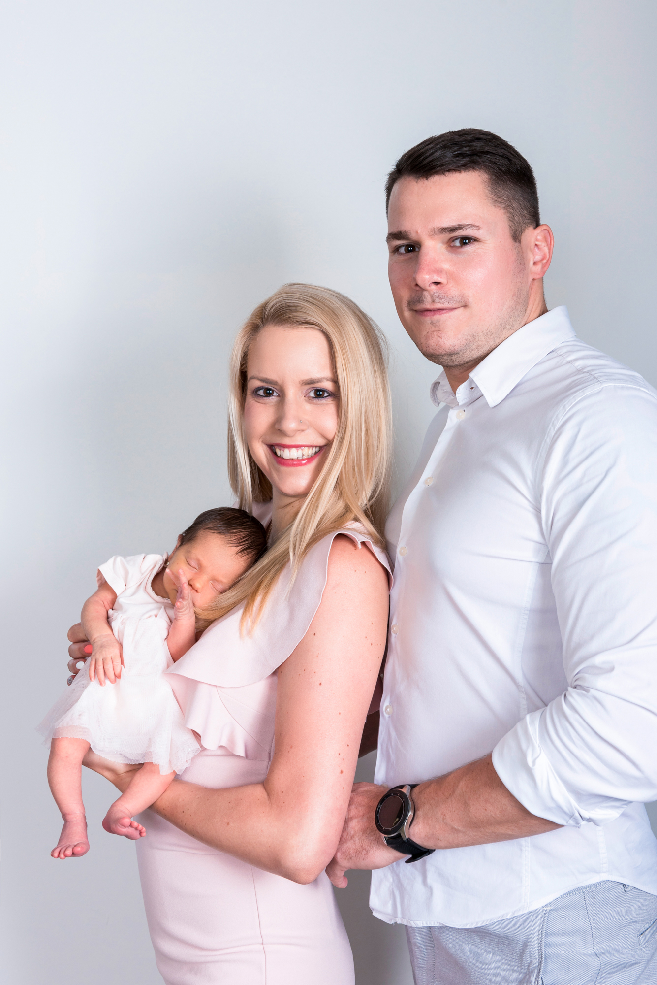 Parents holding newborn baby Kendra during relaxed home newborn session with soft natural tones.