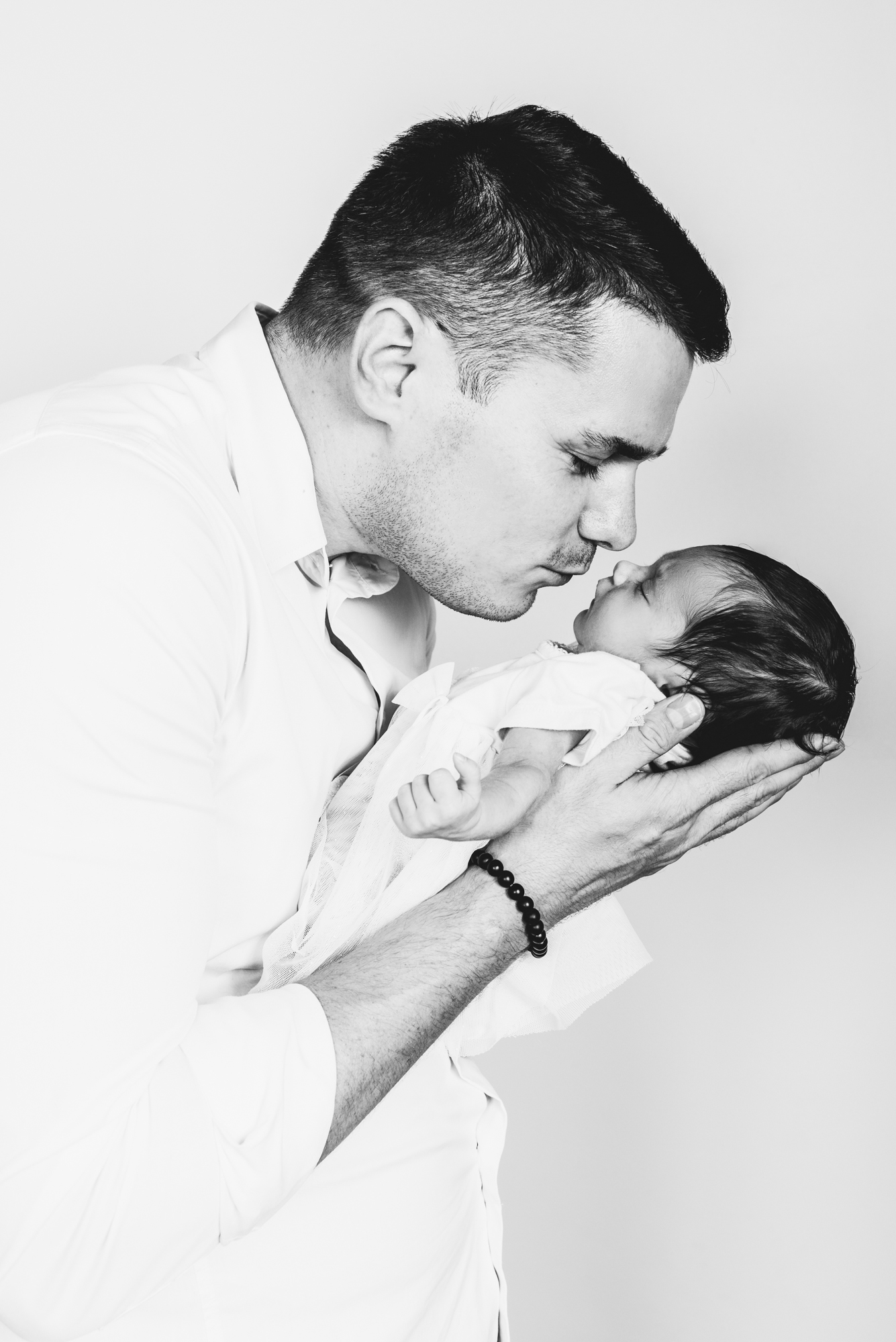 Father gently holding newborn baby close to his face during intimate home newborn session.
