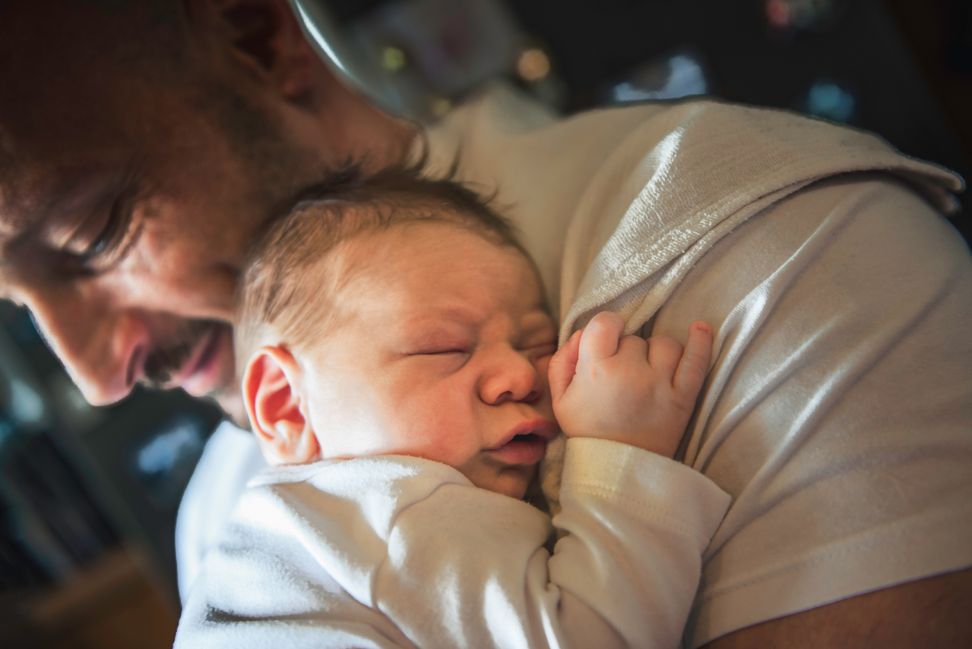 Sleeping newborn rests against dad’s shoulder during an at-home lifestyle newborn session in Bristol.