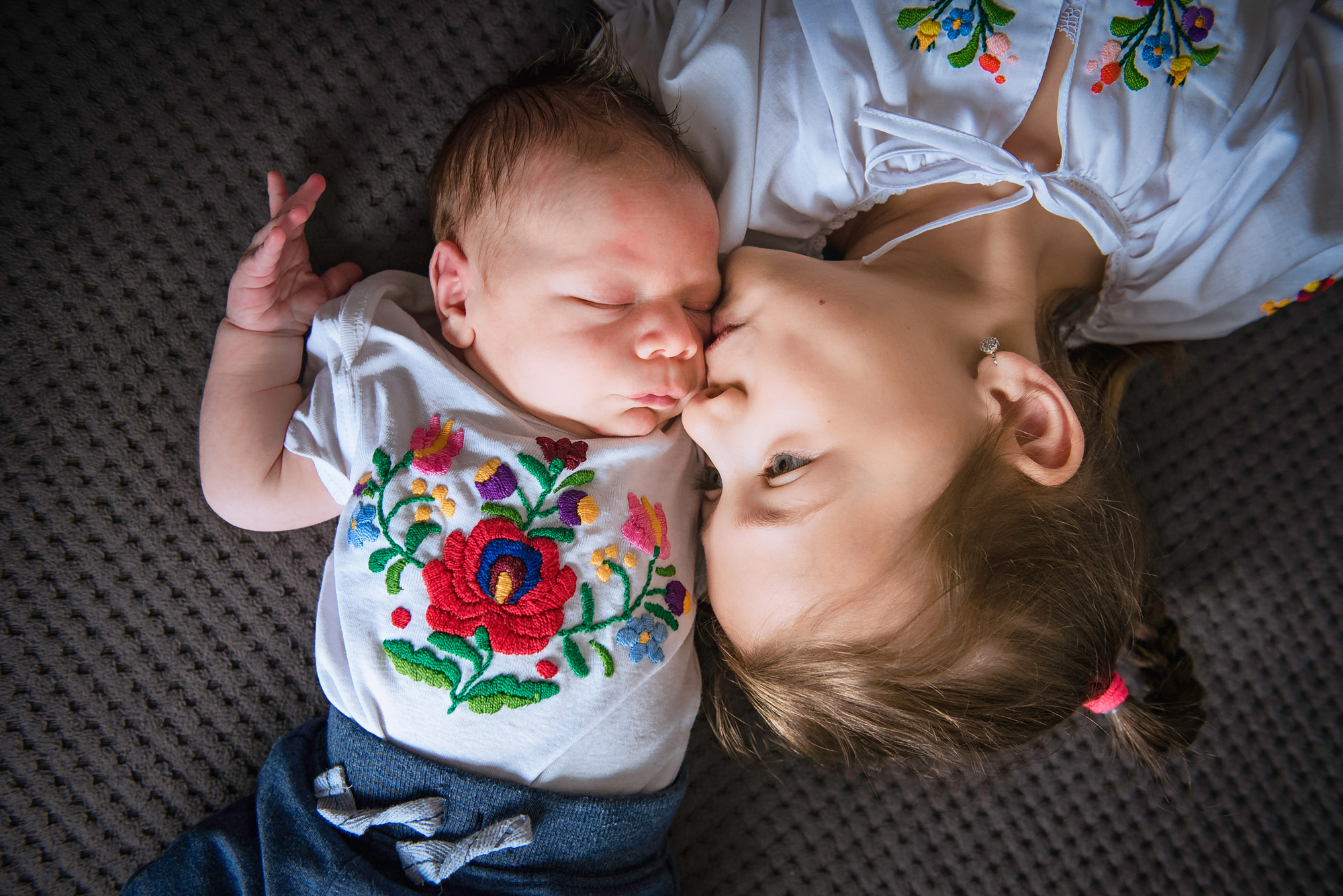Older sister cuddles the newborn during an at-home sibling portrait in Bristol.