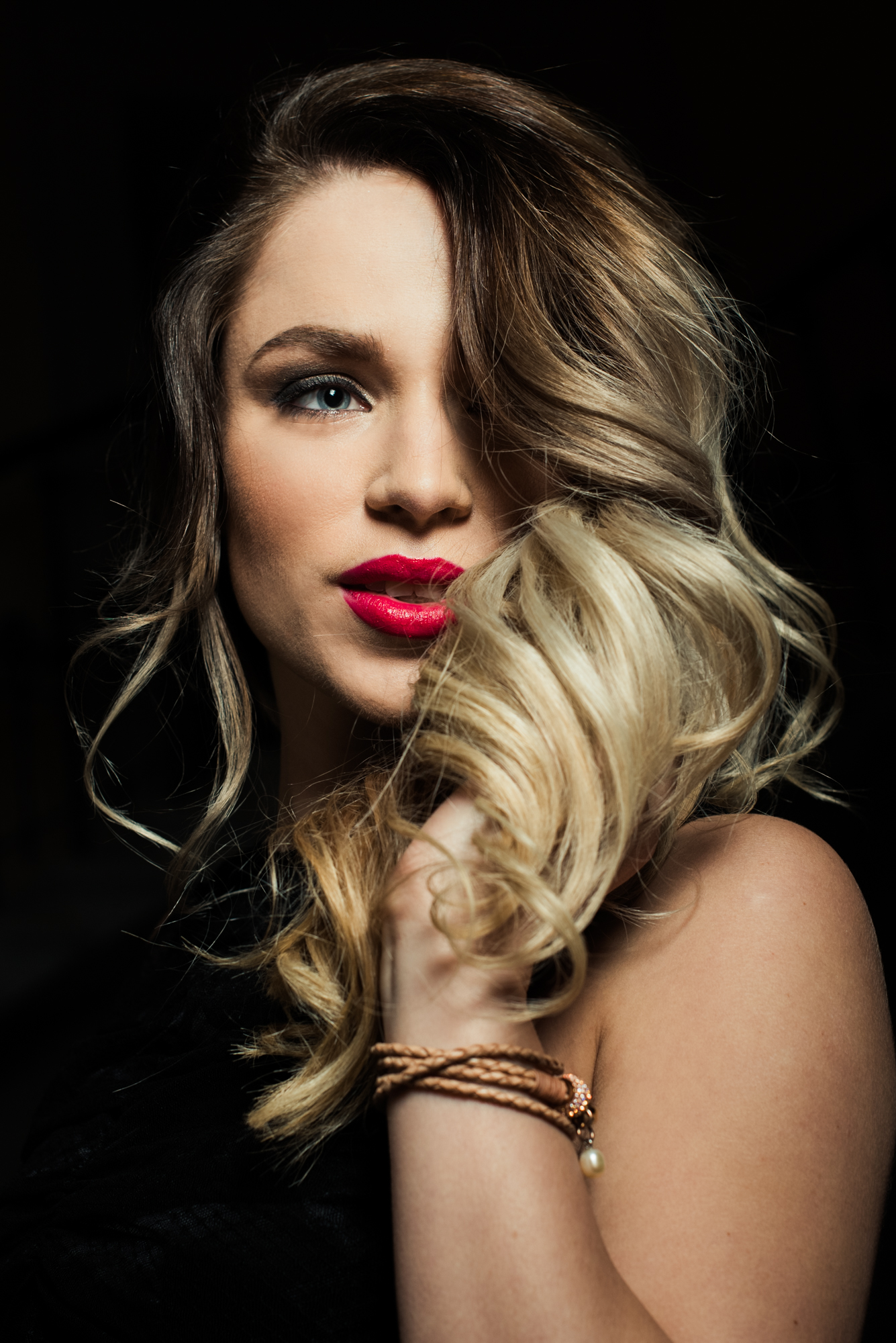 Studio-style close-up with dramatic lighting and textured blonde hair.