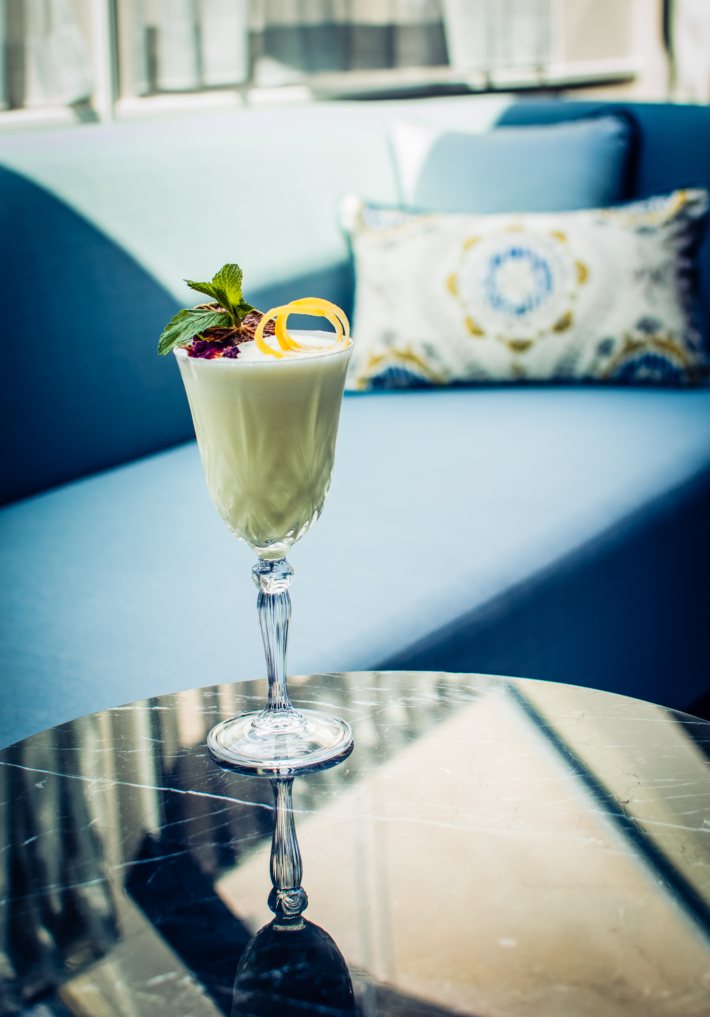Cream cocktail with mint and lemon garnish on marble table at Ritz Carlton Budapest hotel room.