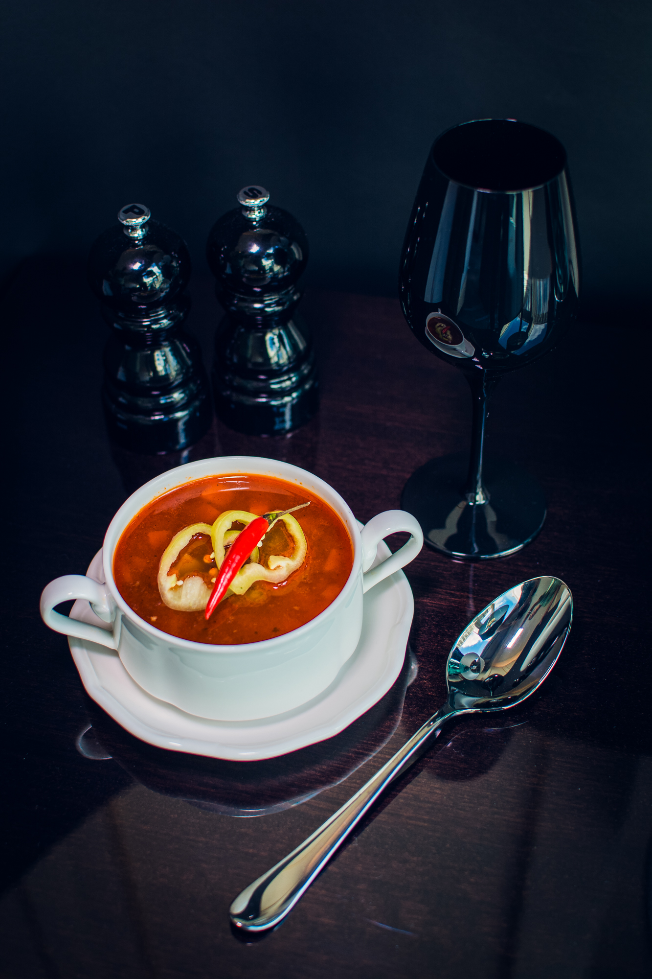 Goulash soup with chilli and lemon served in dark hotel room setting at Ritz Carlton Budapest.