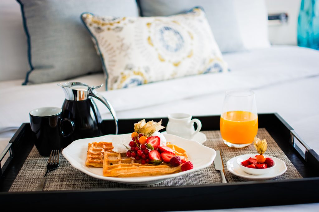 Room service breakfast tray with waffles, berries, coffee, and orange juice in Ritz Carlton Budapest suite.