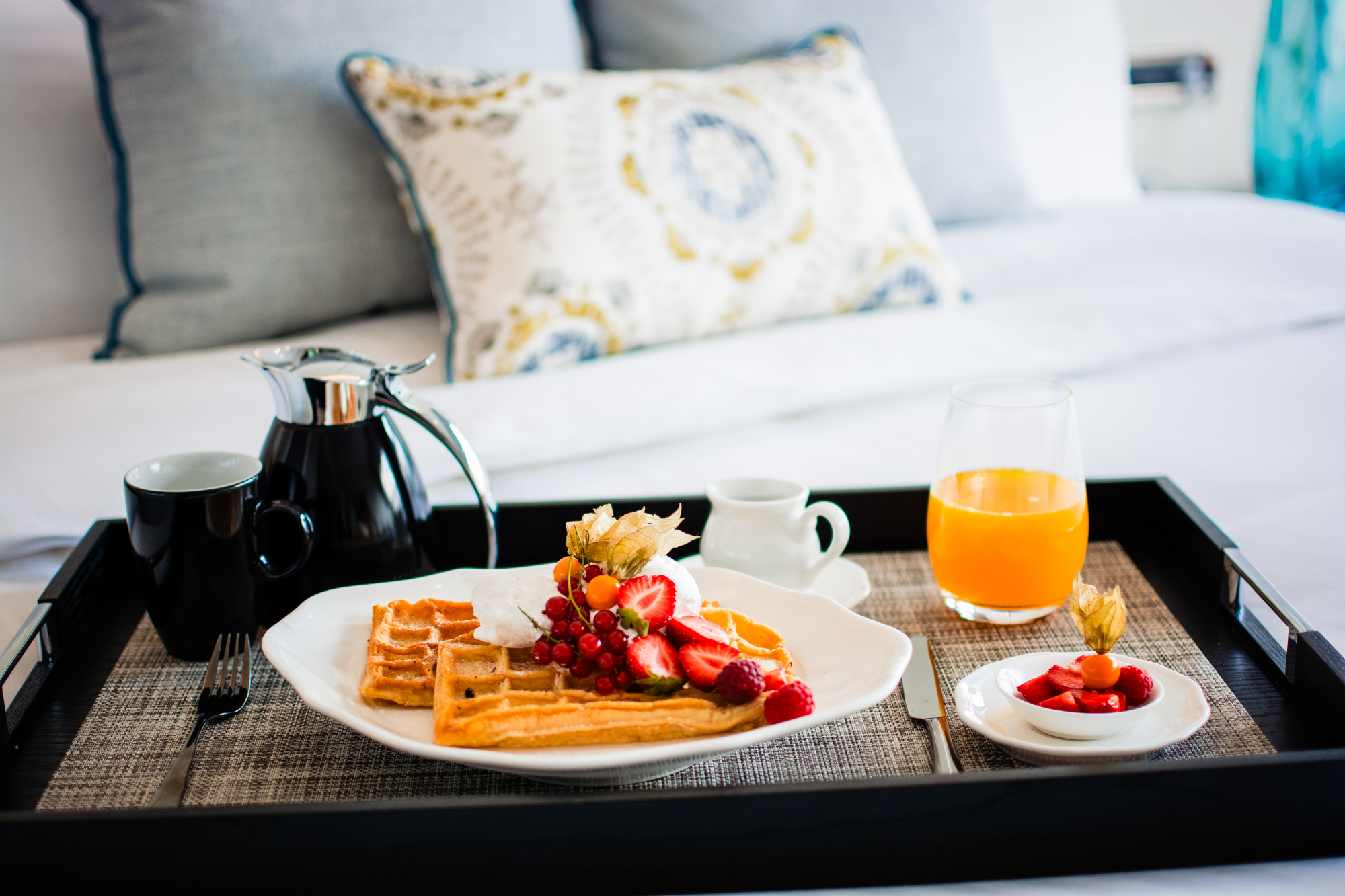 Room service breakfast tray with waffles, berries, coffee, and orange juice in Ritz Carlton Budapest suite.