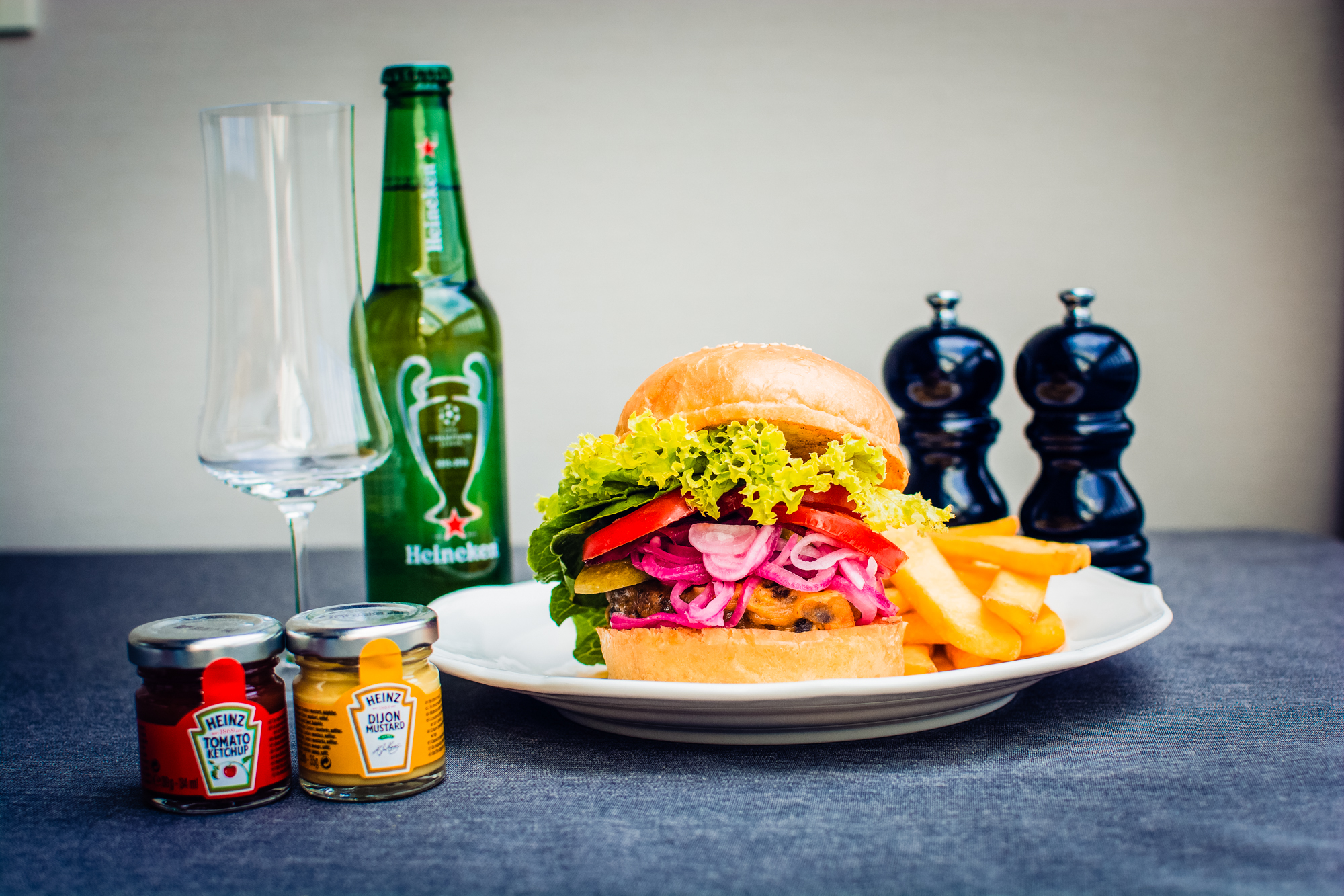 Gourmet burger with fries, pickled onions, and beer photographed for Ritz Carlton Budapest room service menu.