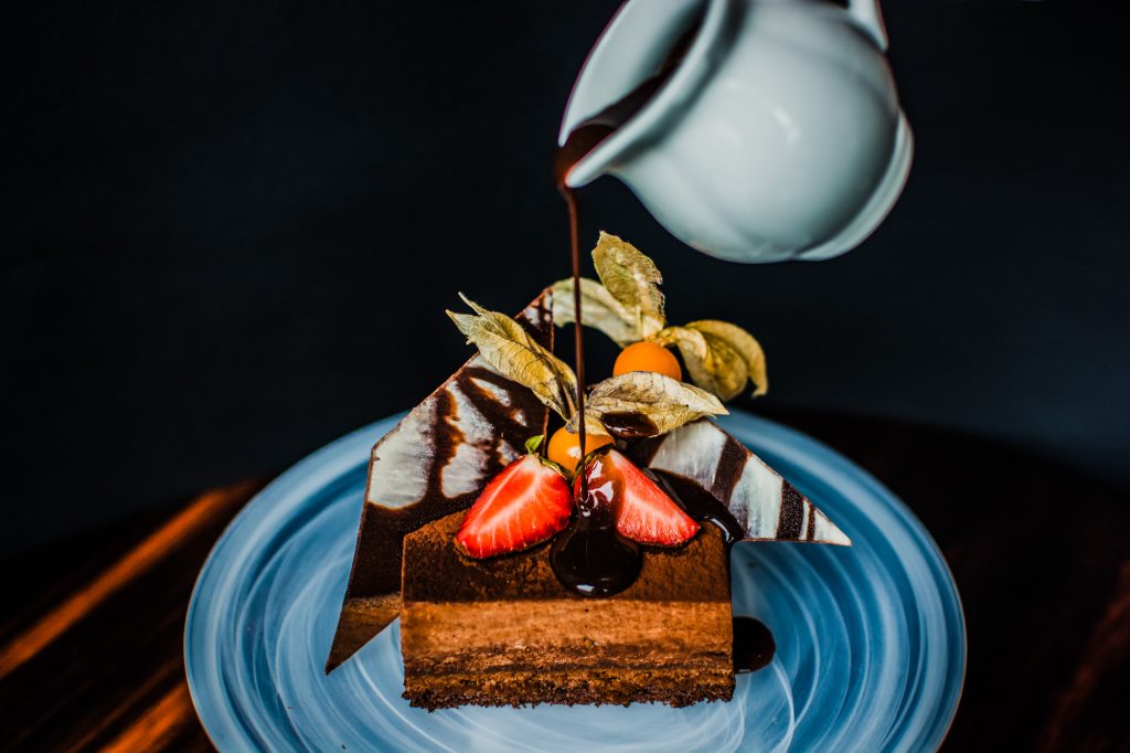 Chocolate dessert with strawberries and sauce pouring over layered cake at Ritz Carlton Budapest.