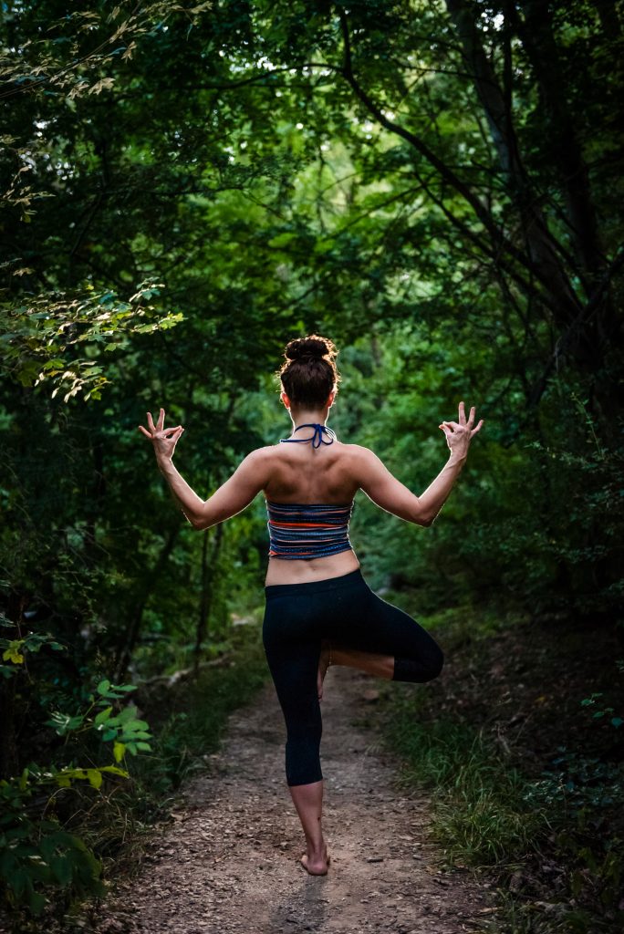 Yoga teacher balancing barefoot in tree pose outdoors at Three Border Mountain in Budapest.