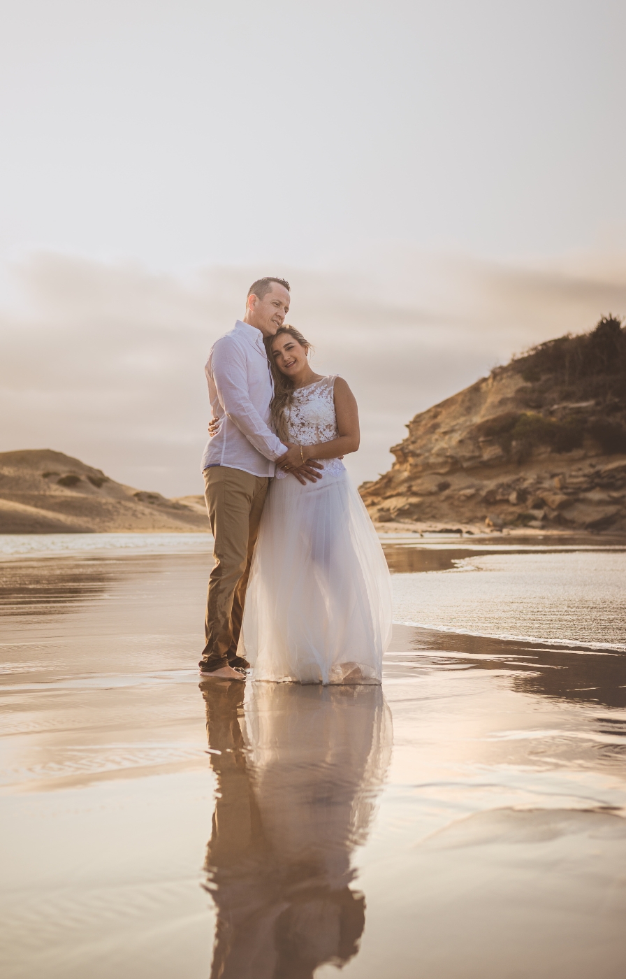 Couple embracing on a sandy beach at sunset, capturing the joy and intimacy of eloping in the UK.