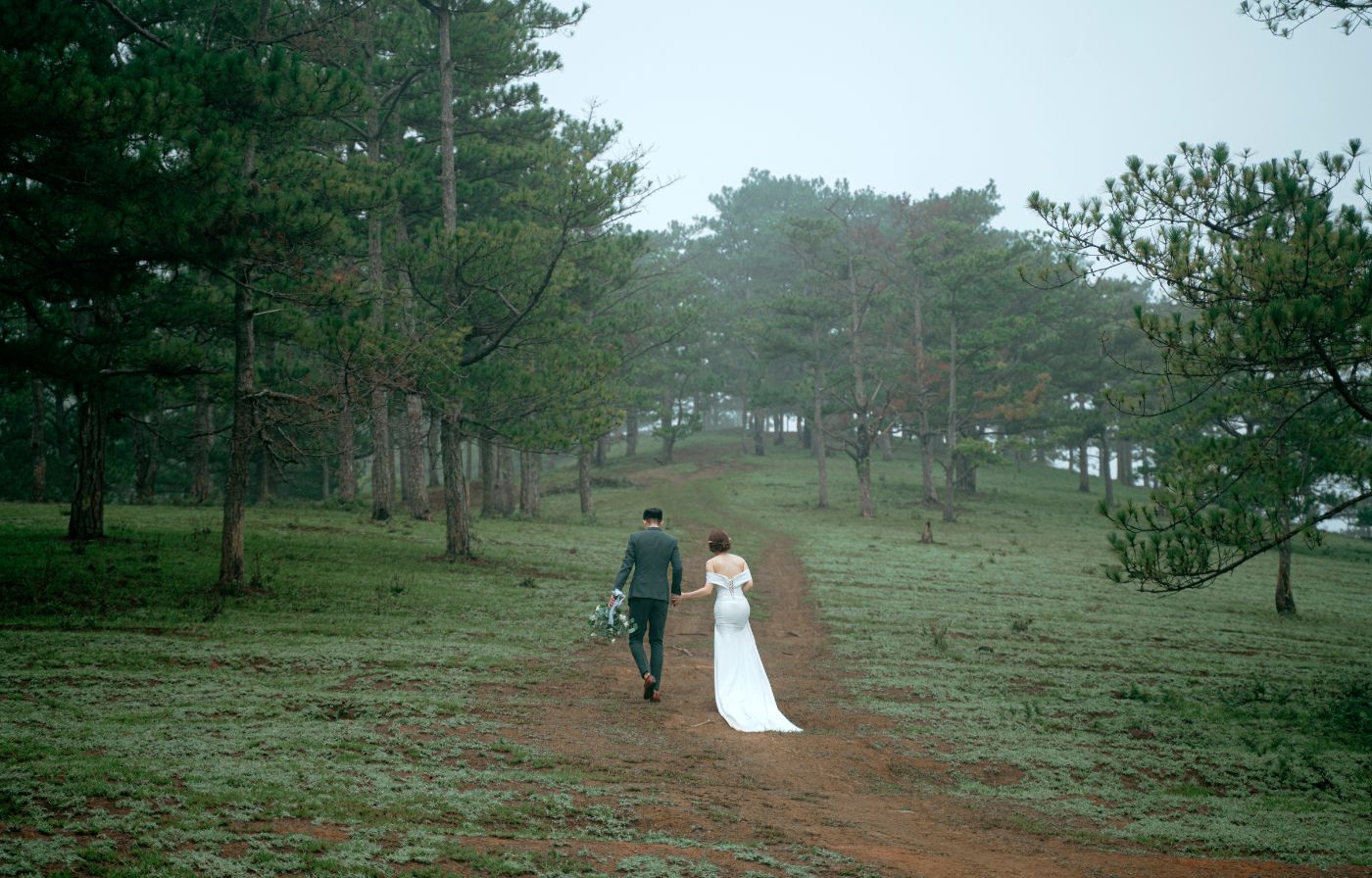 Bride and groom walking hand in hand along a woodland path, a romantic forest escape for eloping in the UK.