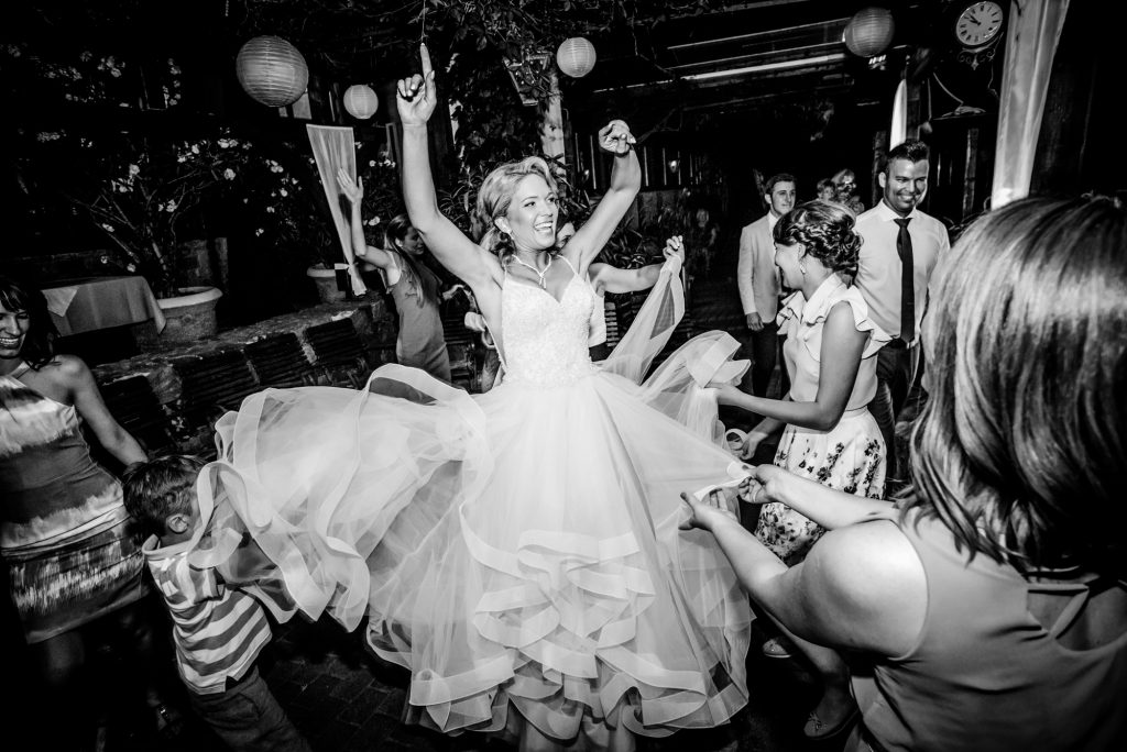 Bride twirling on the dance floor, dress flowing as guests cheer around her in celebration.