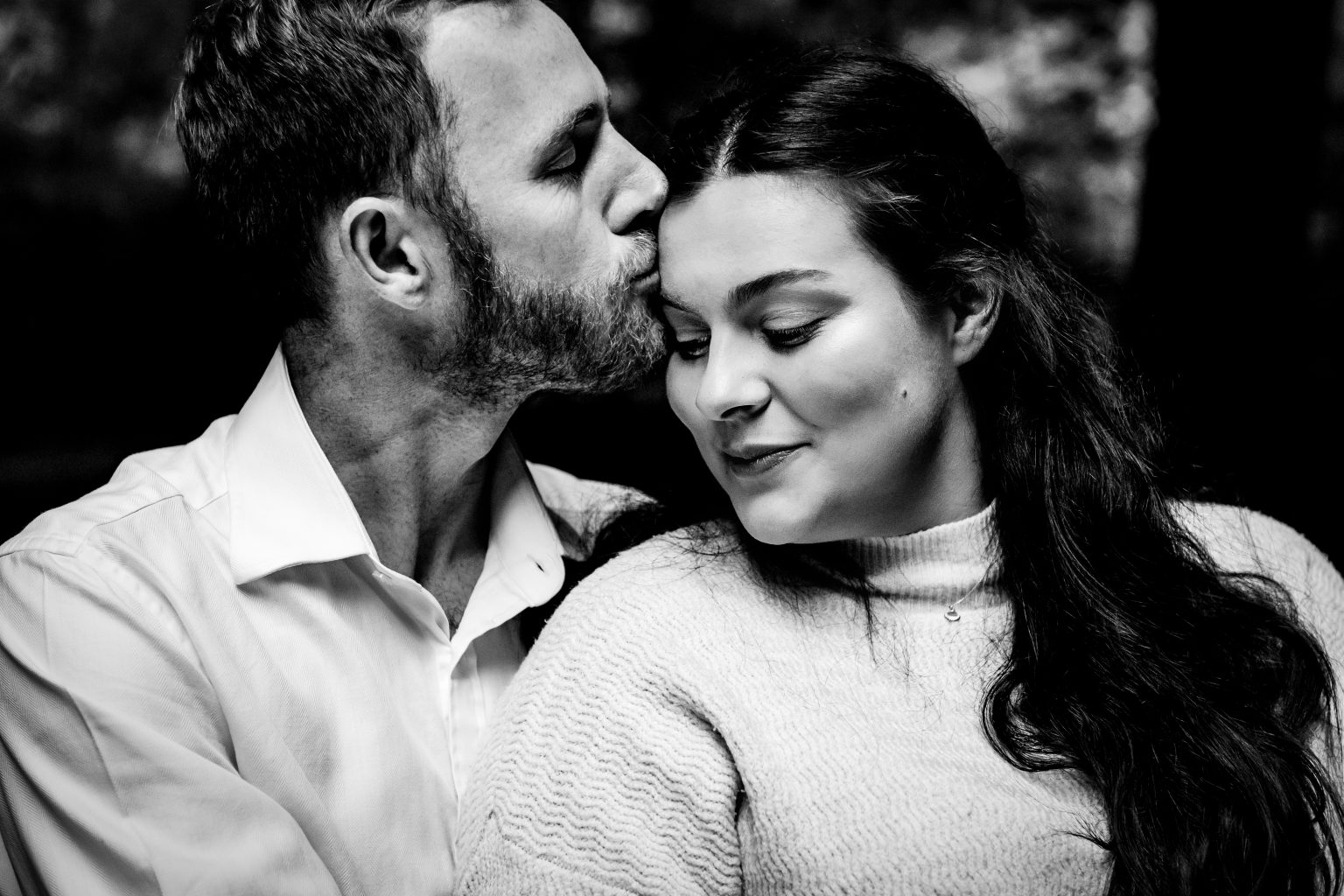 Romantic engagement photo of a couple cuddling as he kisses her forehead, captured in a quiet moment during their Bristol couples photography session.