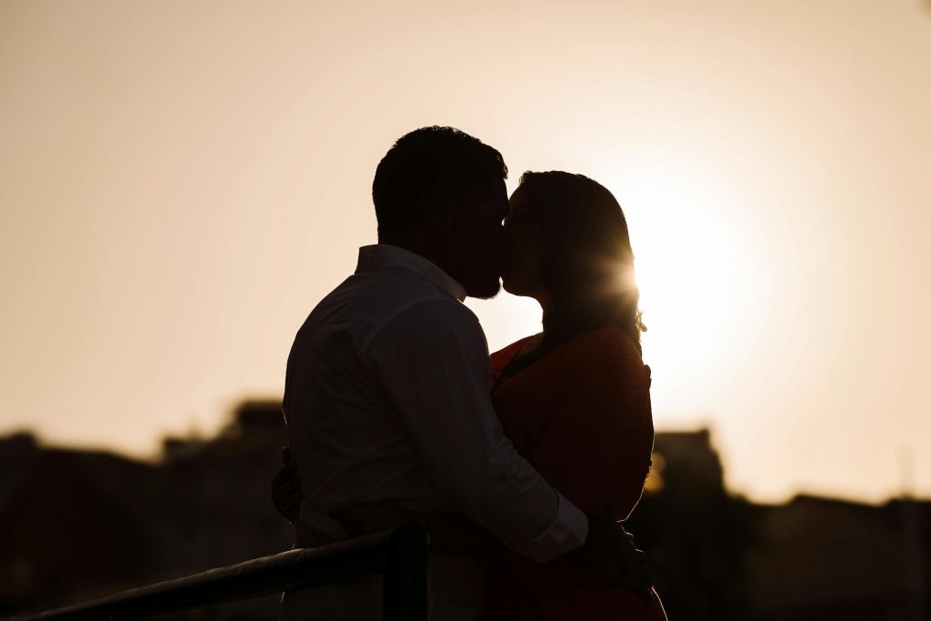 Silhouette of a couple kissing outdoors with the sunset in the background