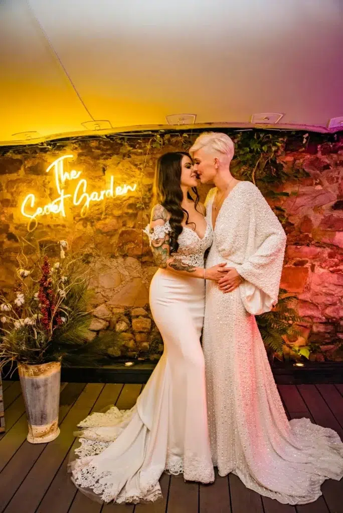 Tattooed brides sharing a kiss under neon lights by wedding photographer at the Square Club in Bristol