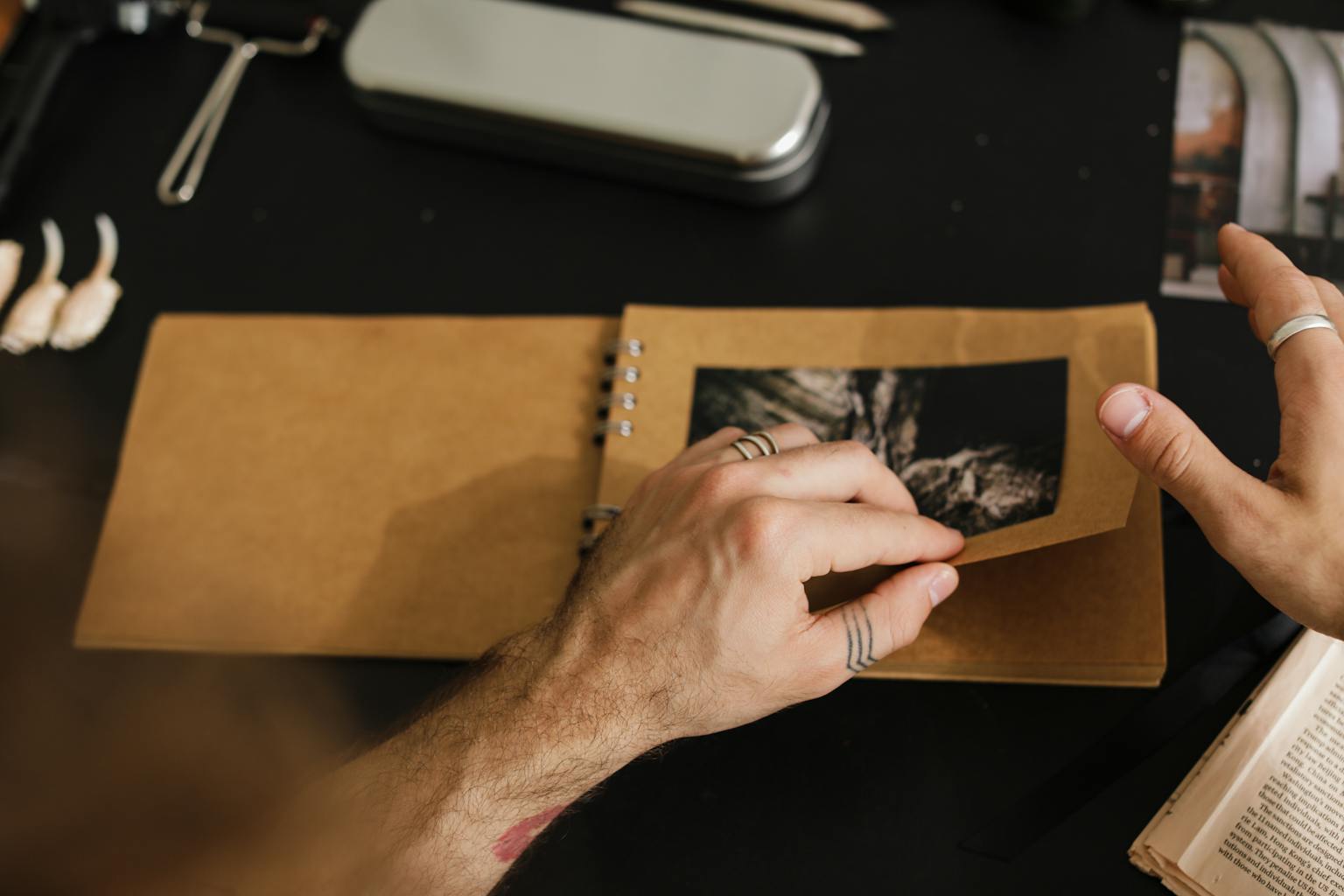 Close-up of hands flipping through a brown photo album on a black surface.