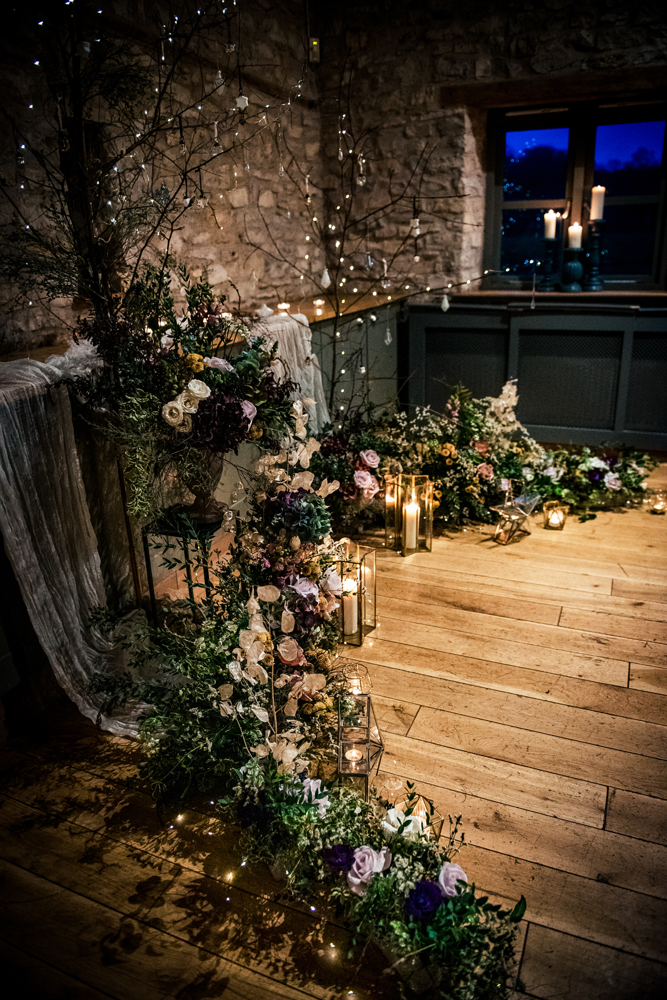 Romantic ceremony corner decorated with lush winter florals, candles, and twinkling lights at Folly Farm.
