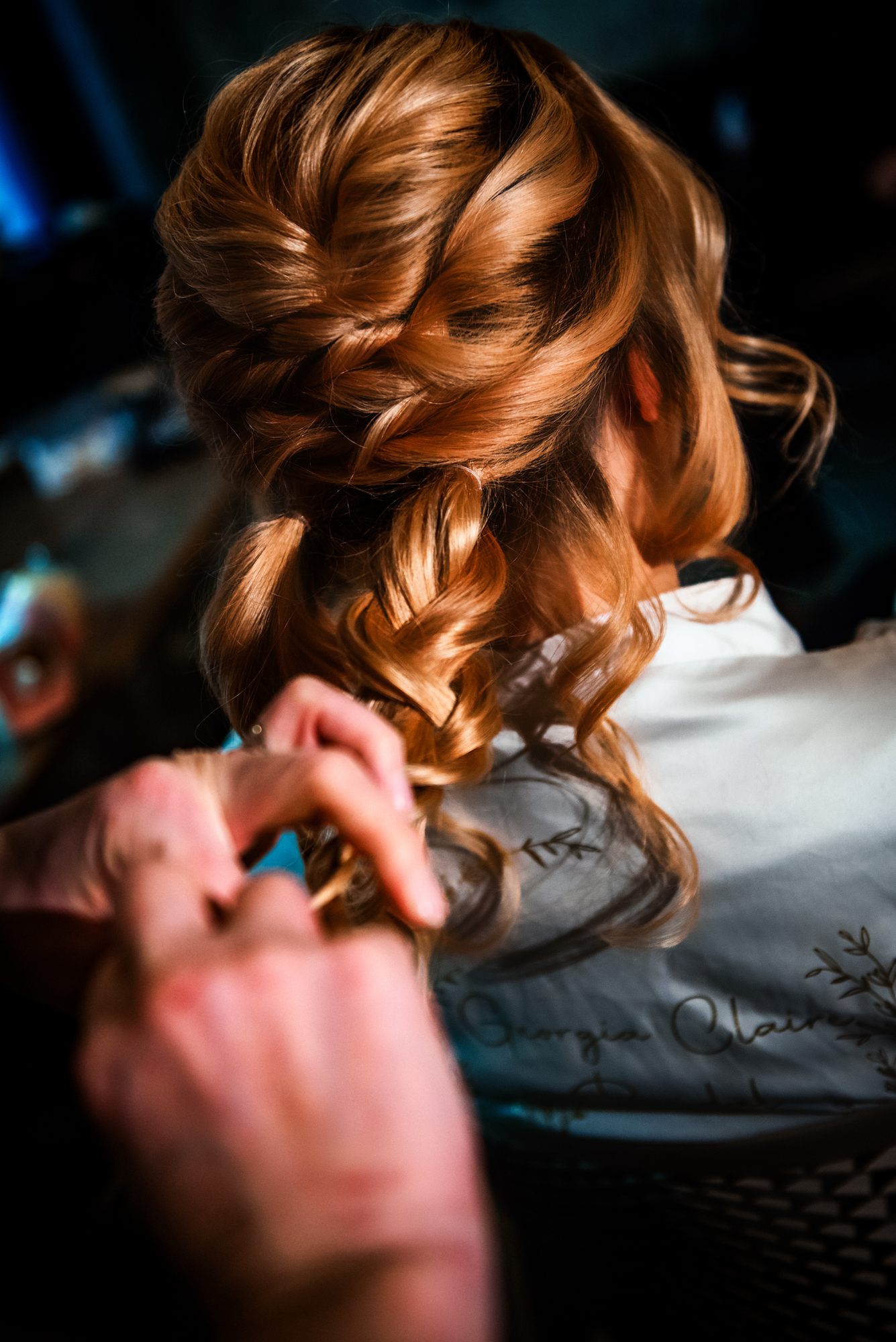 Intricate braided bridal hairstyle being perfected under warm studio lighting.