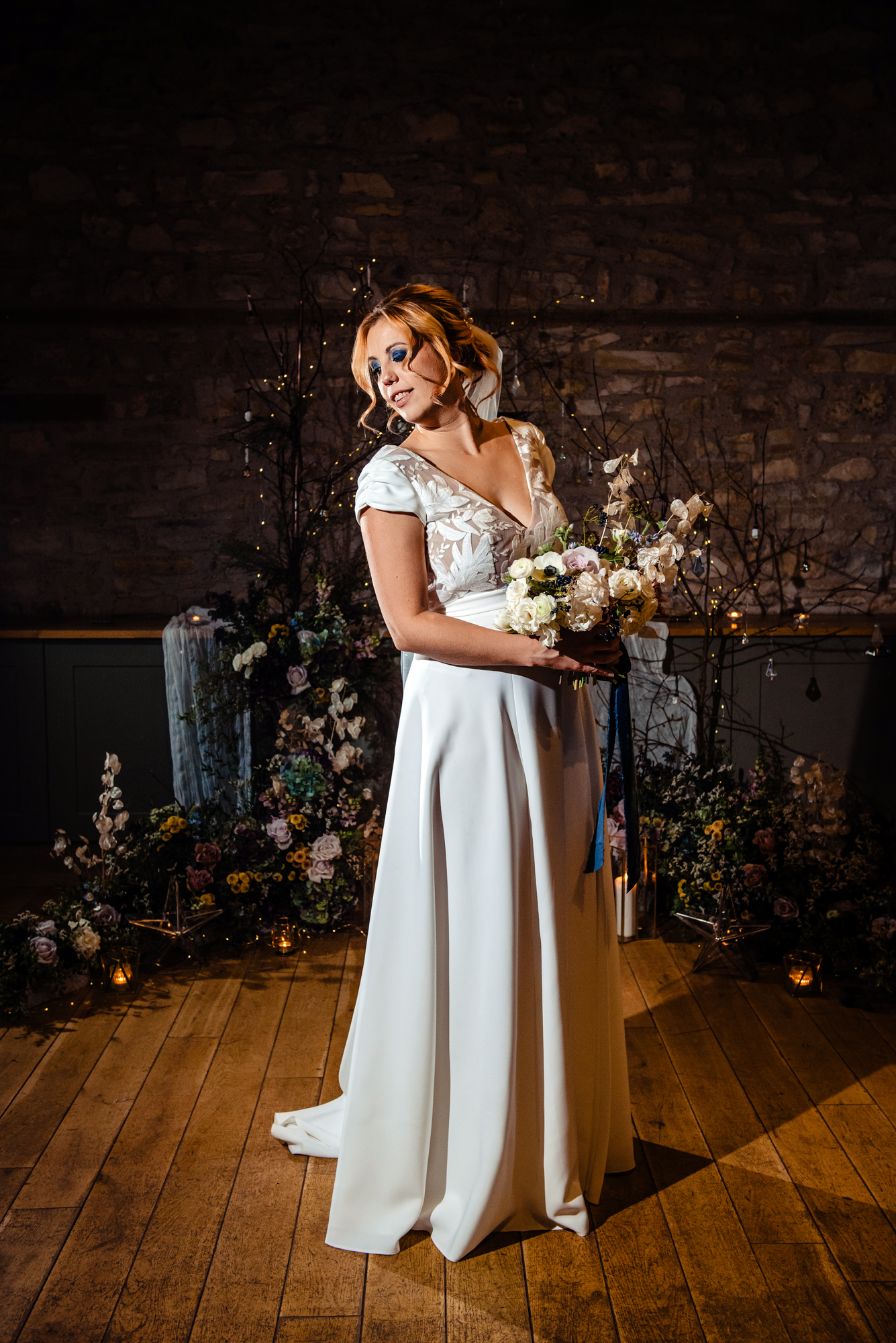 Bride posing with her winter bouquet in front of the floral installation at Folly Farm.