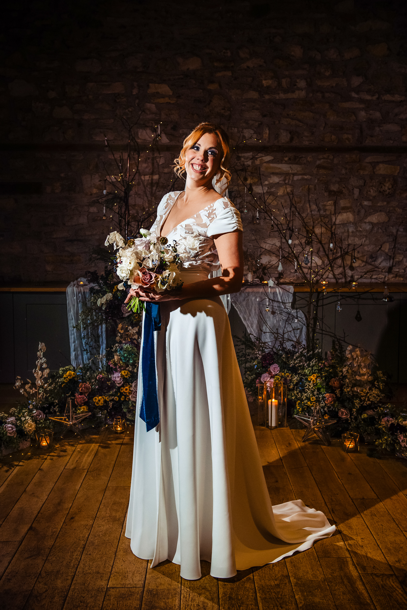 Bride smiling warmly while holding her bouquet in the candlelit Starry Night setup.