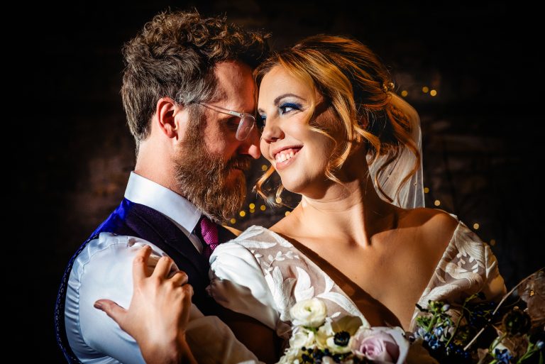 Couple sharing a close, tender moment surrounded by soft candlelight and winter florals.