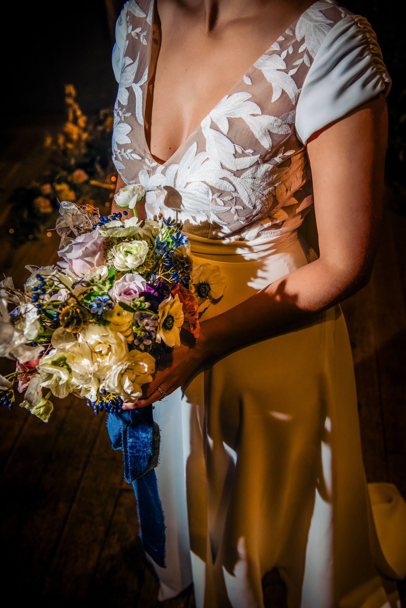 Bride holding a textured winter bouquet of pastel florals, berries, and lunaria stems.