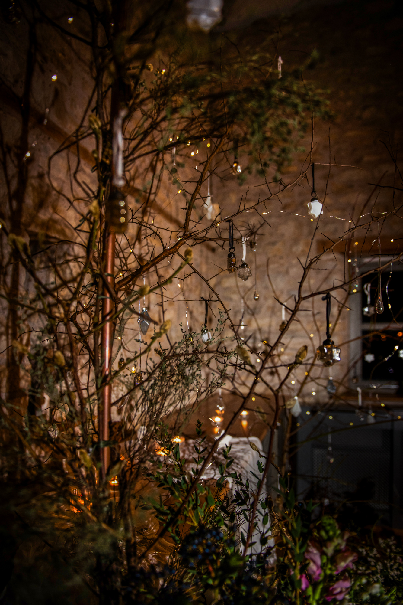 Branches decorated with tiny hanging lights and glass ornaments in the venue.