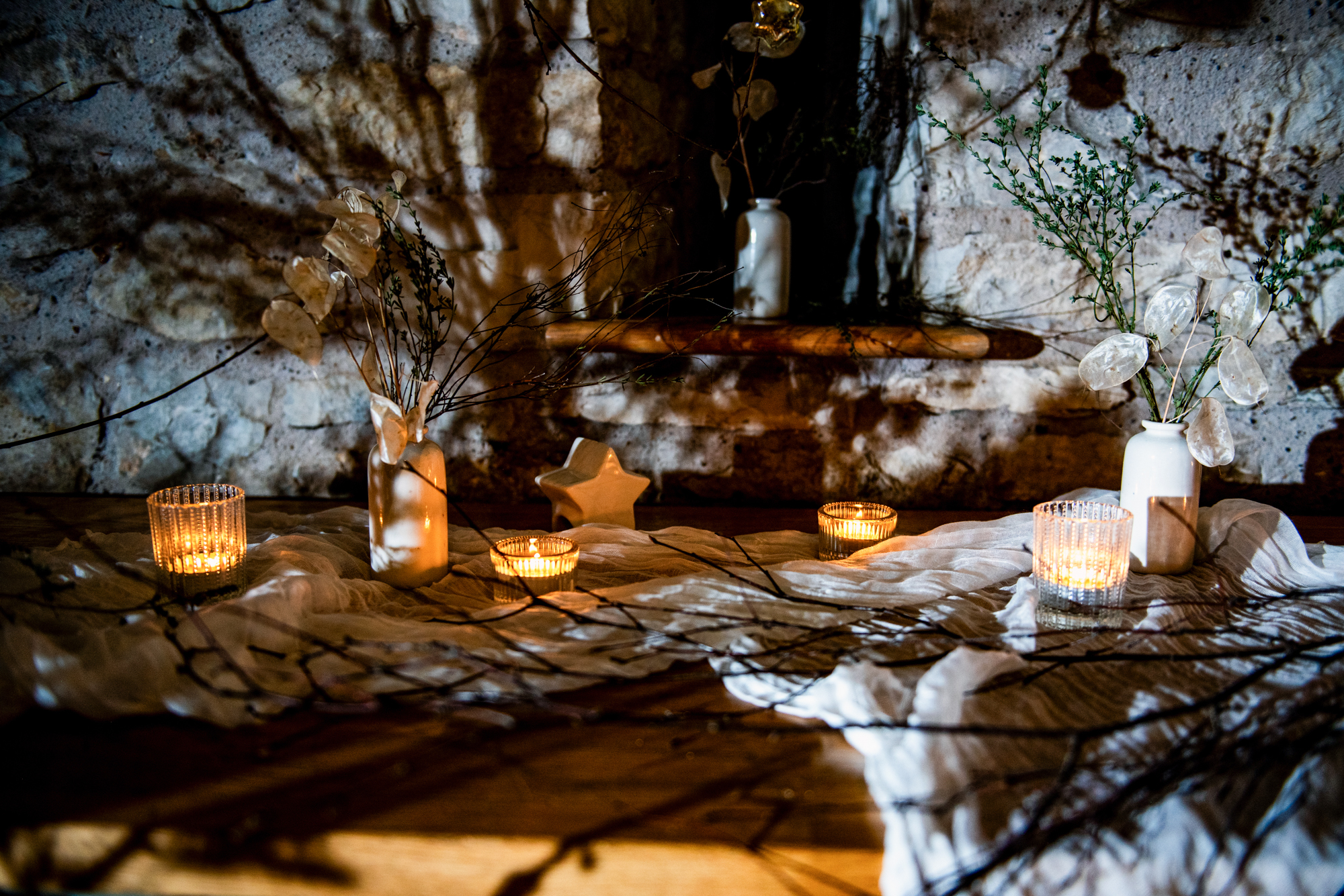 Textured linen, candles, and dried stems styled on a rustic table for detail shots.