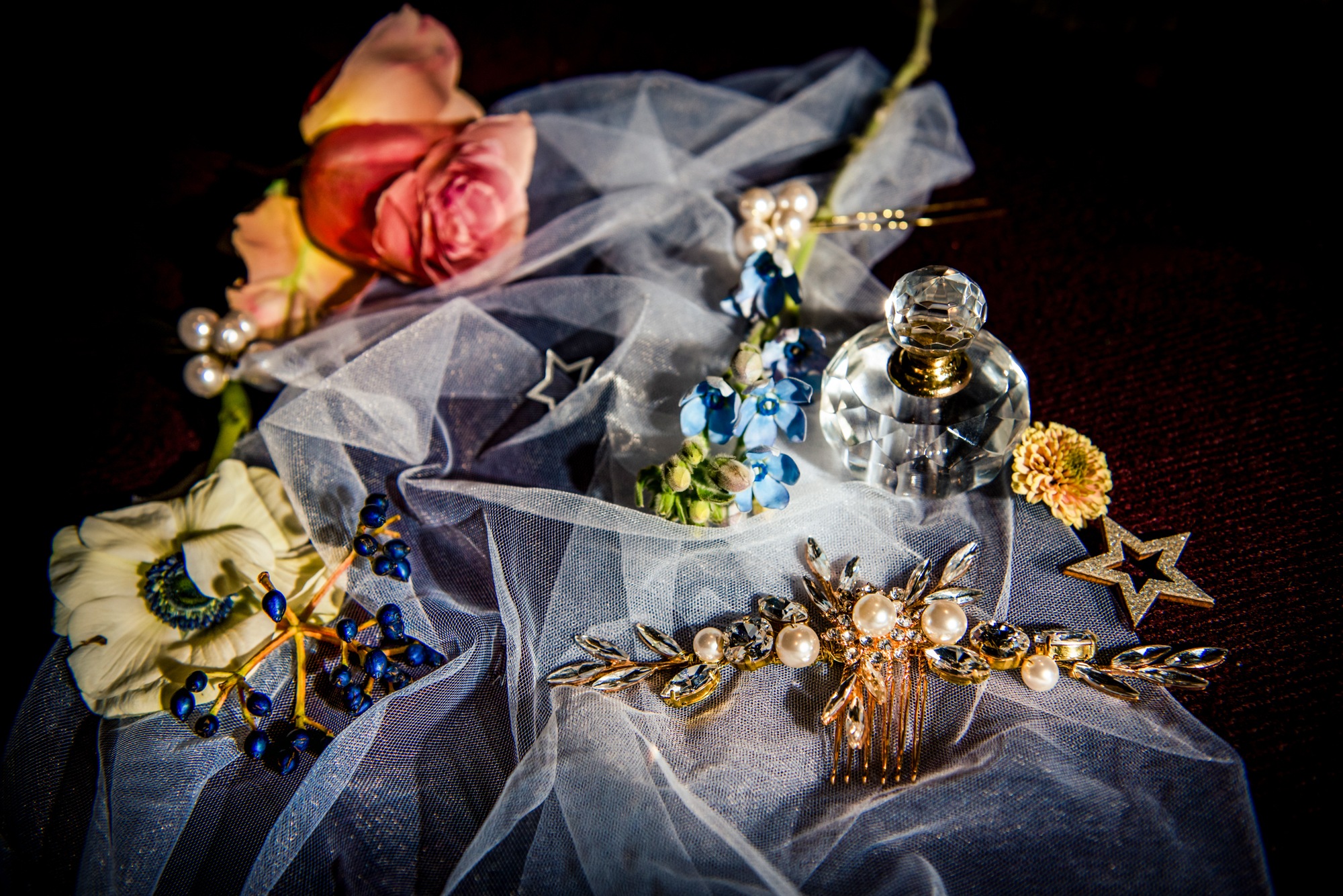 Perfume bottle, flowers, and celestial accessories arranged on draped tulle for bridal detail styling.
