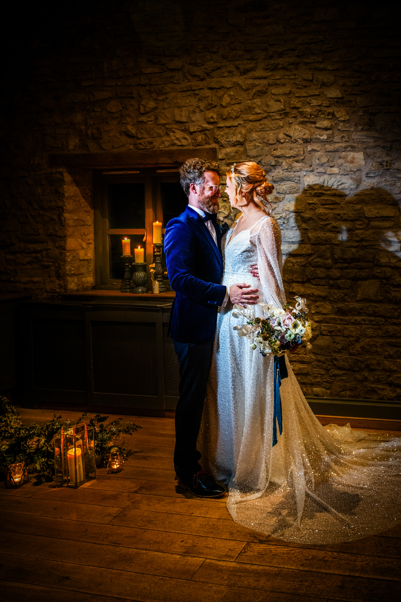 Couple sharing a quiet moment indoors surrounded by candlelight and winter floral arrangements.