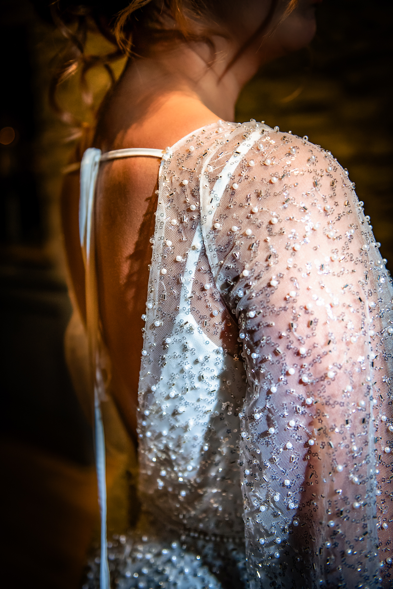 Close-up of pearl-beaded sleeves and delicate back ties of the shimmering celestial wedding gown.