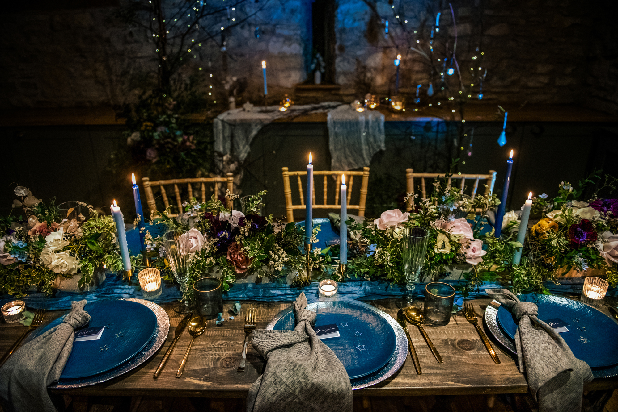 Winter wedding tablescape featuring textured linens, pastel blooms, and glowing candlelight in the stone barn.
