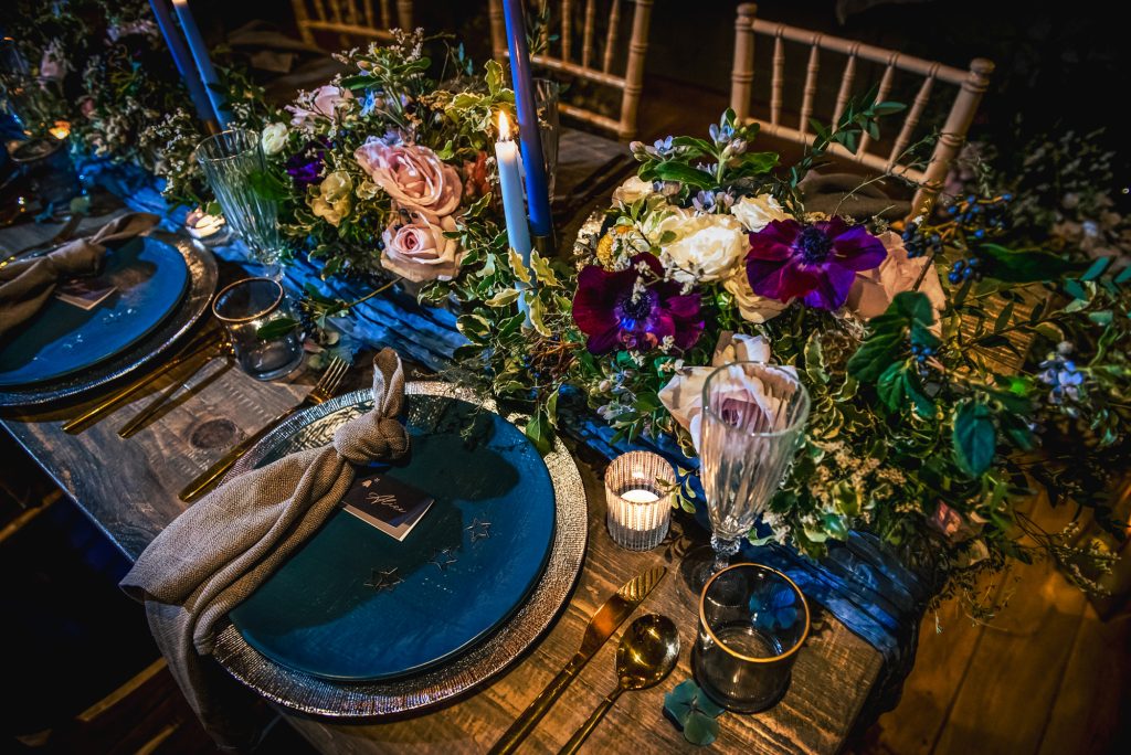 Detailed close-up of florals, candles, and blue taper candles creating a celestial winter tablescape.