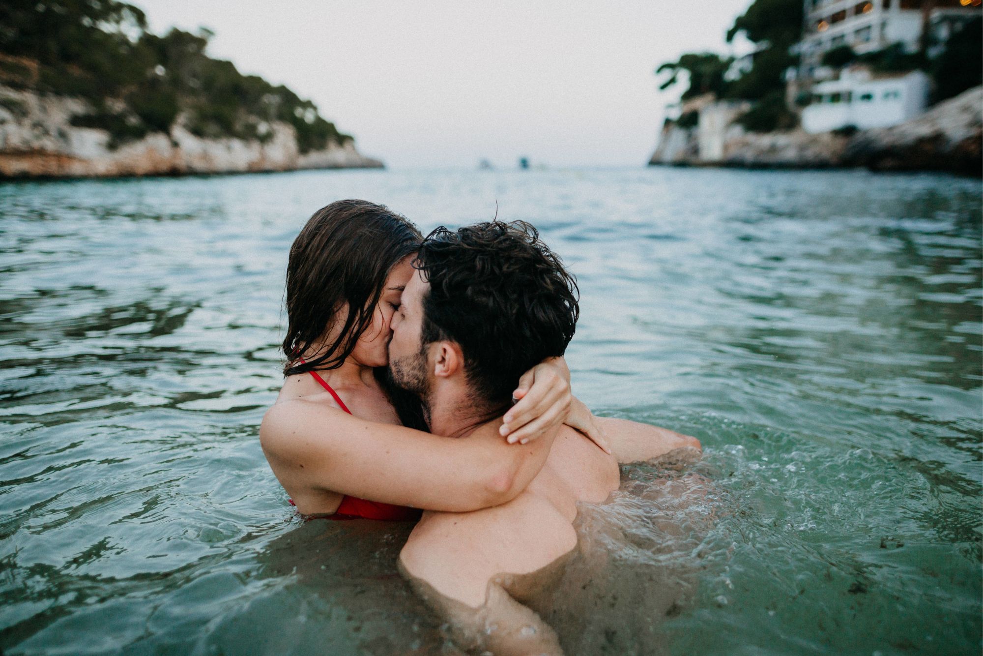 Couple kissing in the sea during a playful beach couple photoshoot.