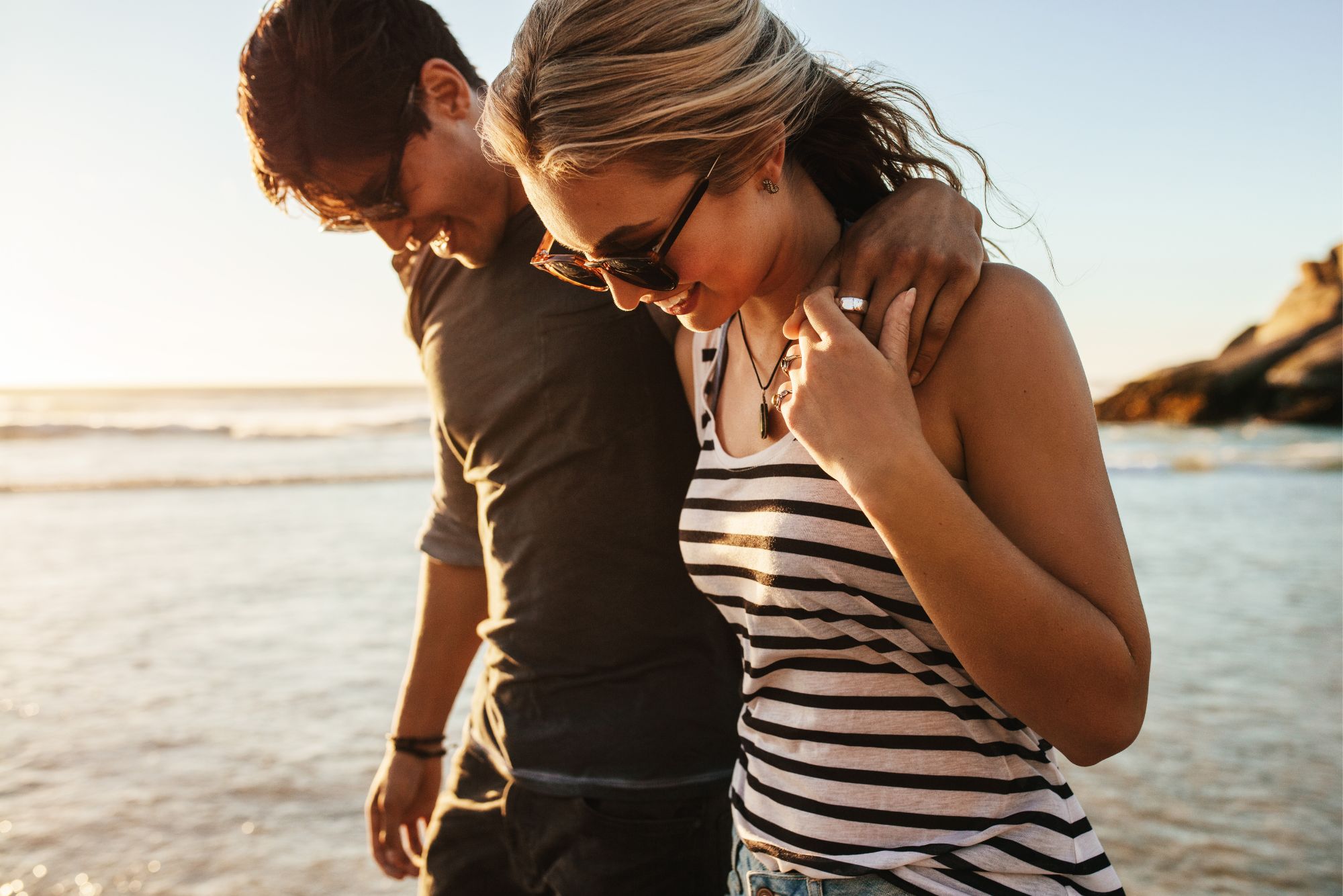 Couple walking along a beach at sunset during a relaxed seaside couple photoshoot.