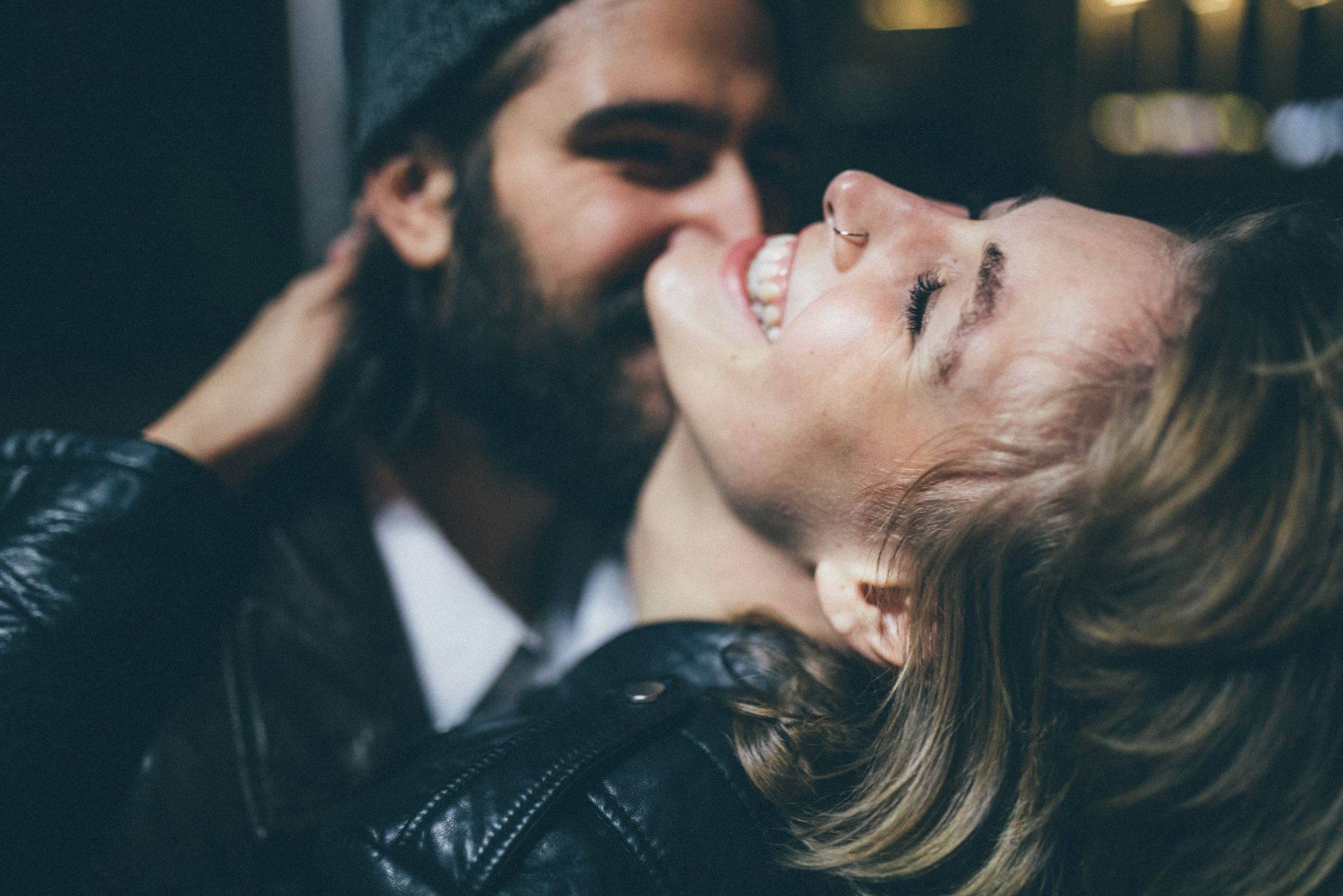 Couple laughing together during an intimate urban couple photoshoot with soft evening street lighting.