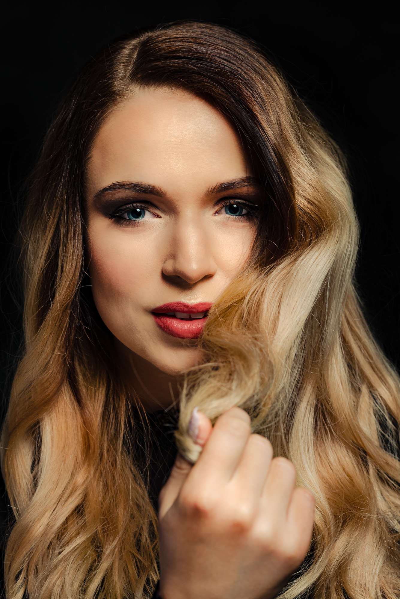 Close-up from a studio portrait session with soft light and curled blonde hair.