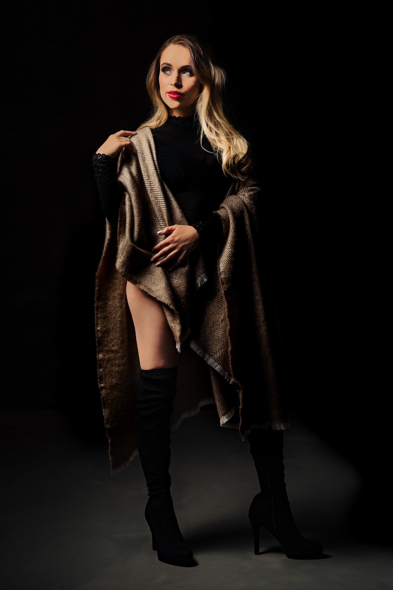 Full-length studio portrait of a woman in boots and shawl with dramatic low-key light.